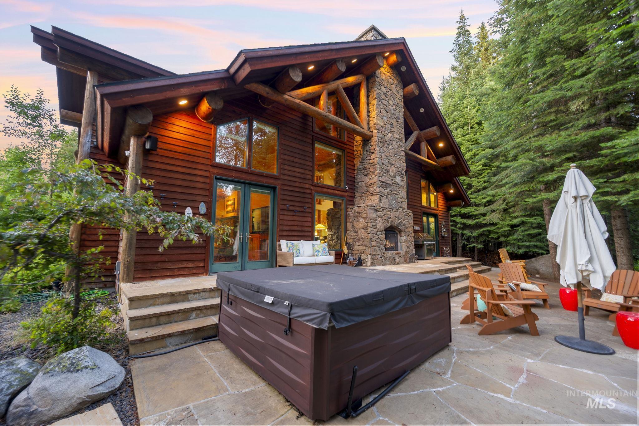 Back of house at dusk featuring a hot tub, a patio area, and french doors