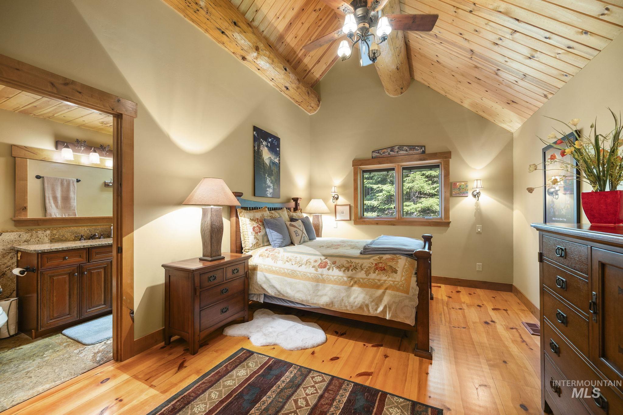Bedroom featuring wooden ceiling, light wood-style floors, and connected bathroom