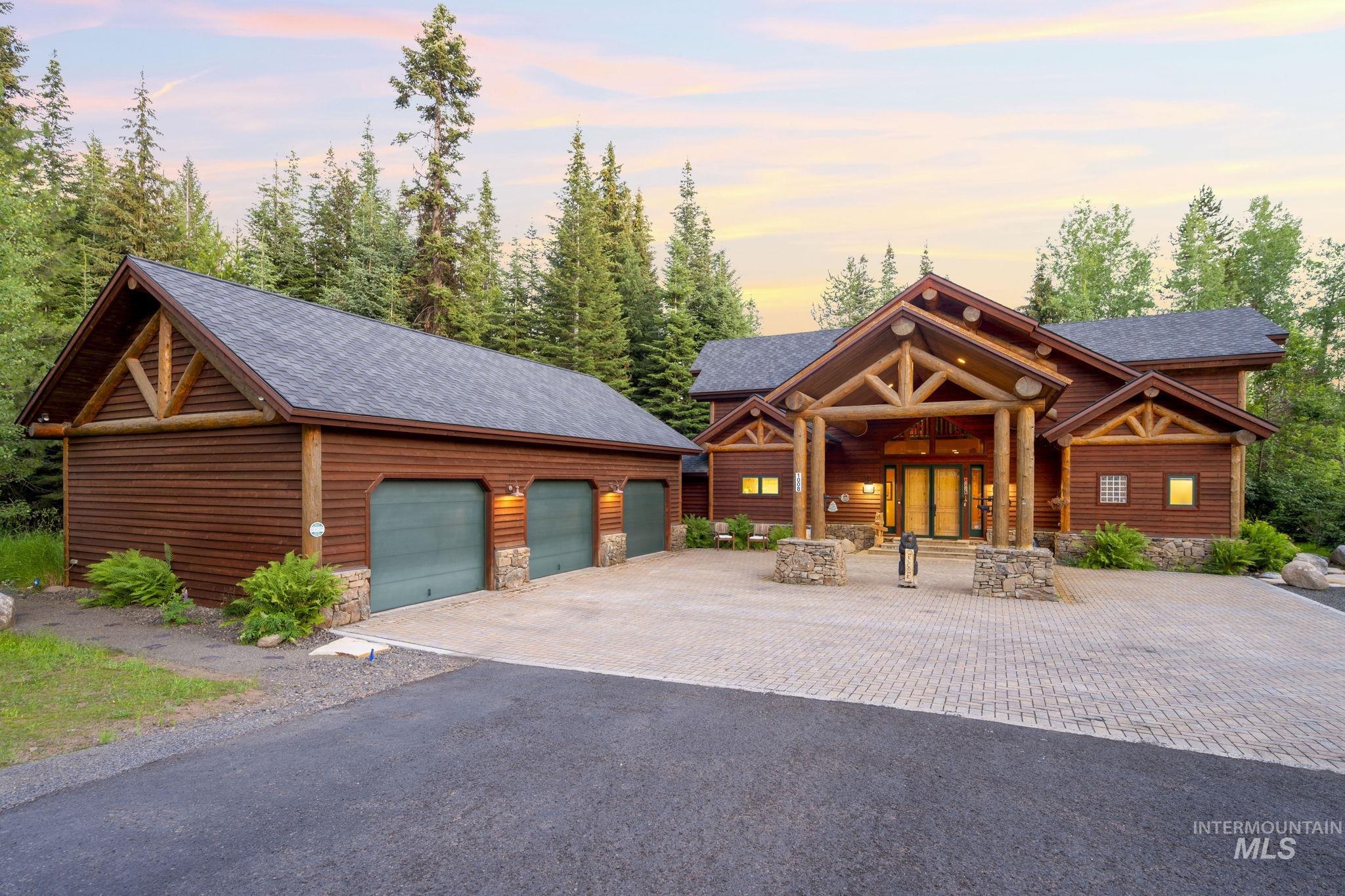 Log home featuring stone siding, an outdoor structure, a garage, driveway, and a shingled roof