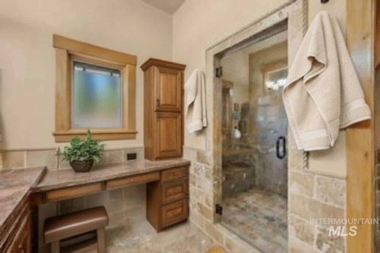 Bathroom featuring vanity, a shower stall, and tile walls