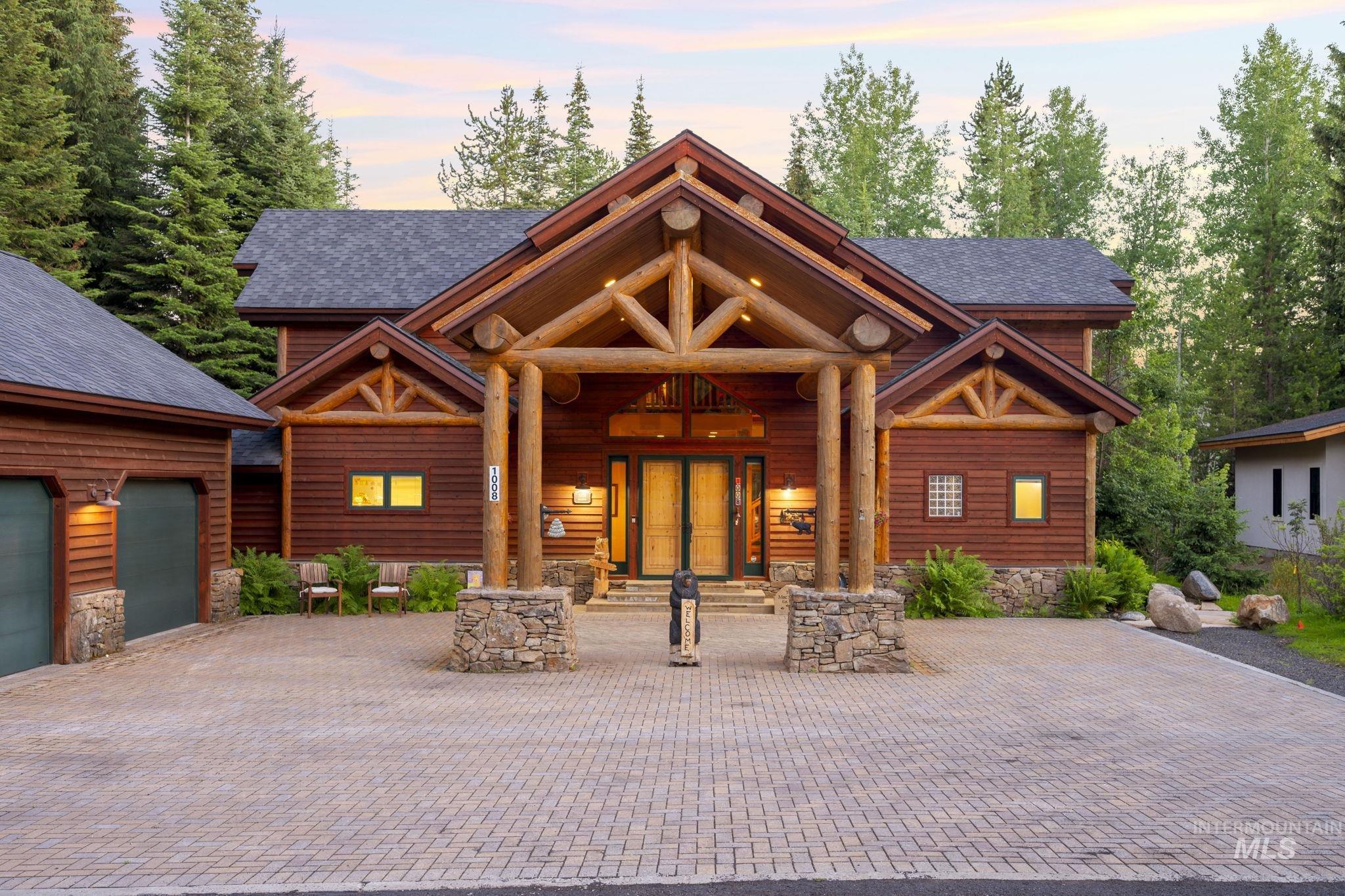 Log home featuring stone siding, decorative driveway, roof with shingles, and french doors