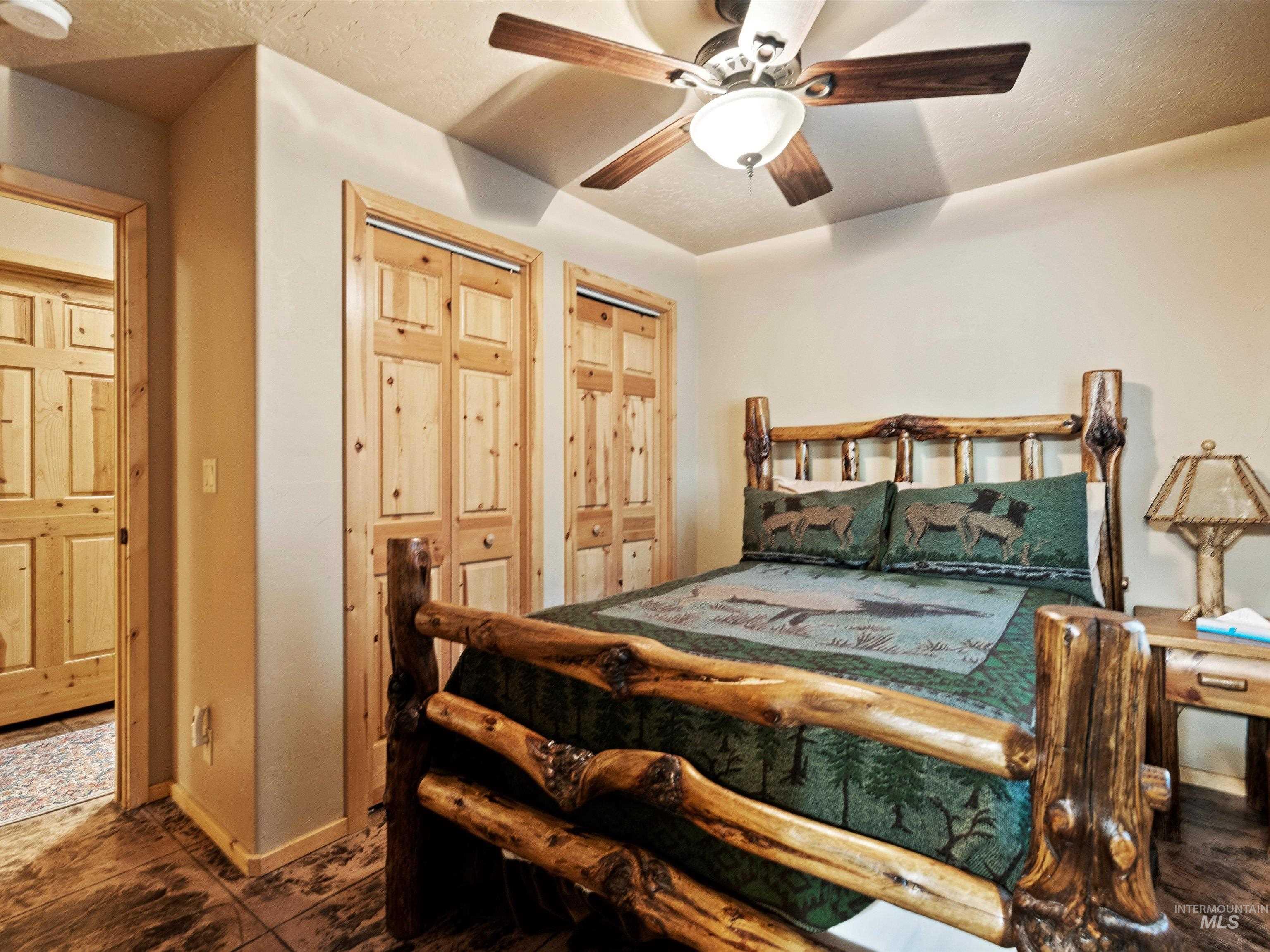 Bedroom with ceiling fan, a textured ceiling, and two closets