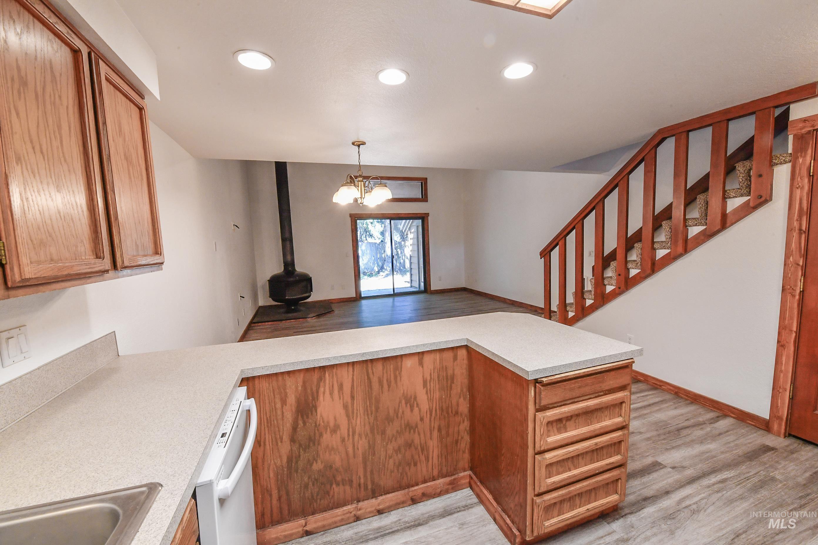Kitchen with light wood-style flooring, a wood stove, a peninsula, and recessed lighting