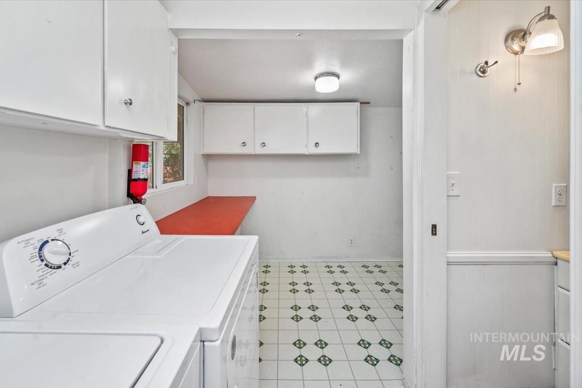 Dedicated laundry area featuring patterned tile flooring and built-in white cabinetry