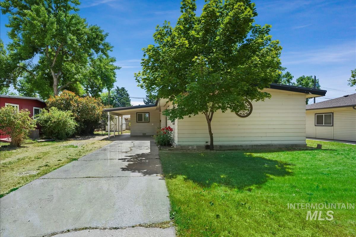Exterior featuring a concrete driveway, covered carport, and mature trees