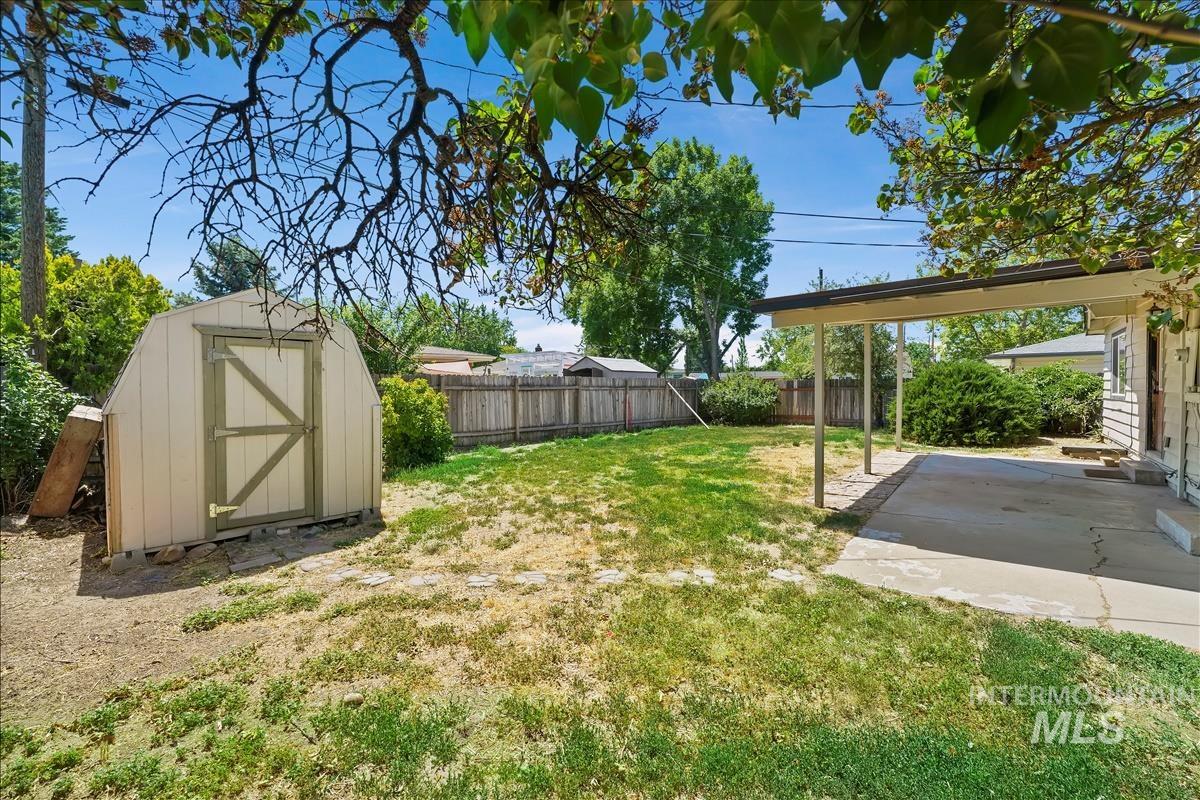 Expansive backyard featuring a storage shed, covered patio, and perimeter fencing