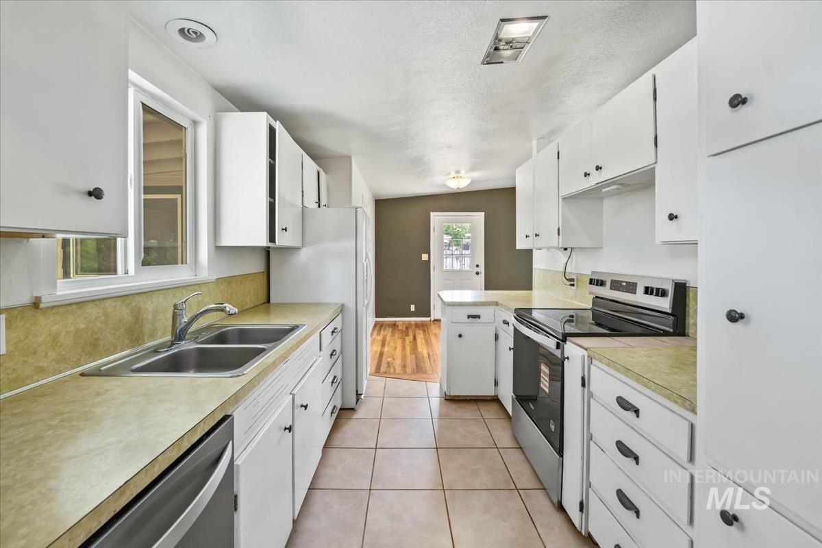 Galley kitchen featuring white cabinetry, light-toned countertops, and tile flooring