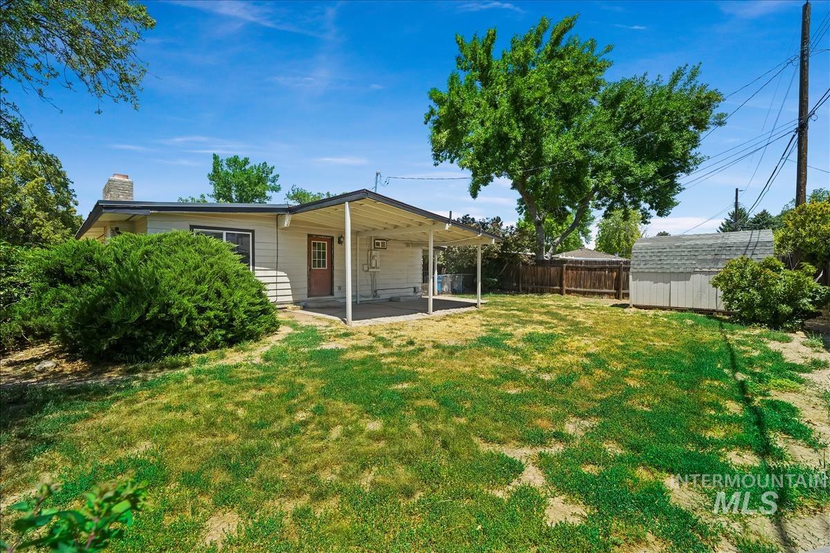 Expansive backyard featuring a covered patio, a detached storage shed, and mature perimeter trees
