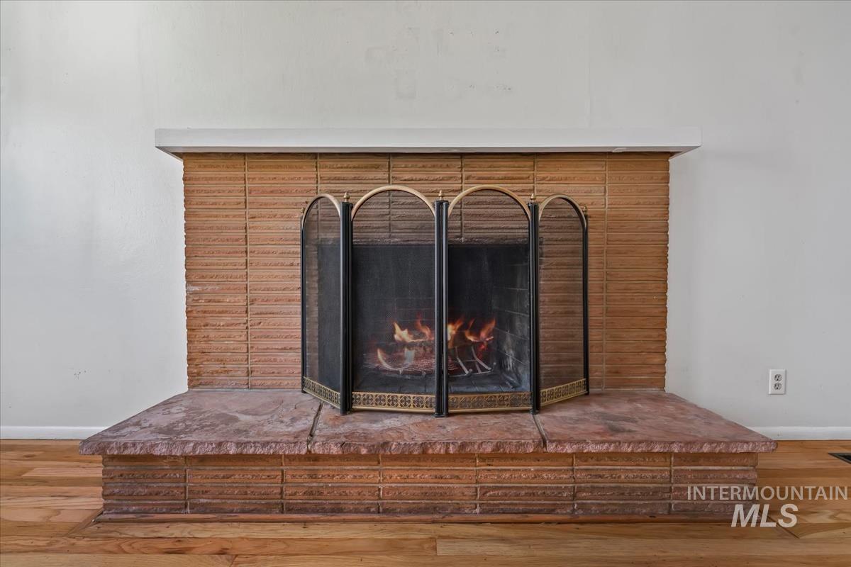 Fireplace featuring a brick surround, white mantel, and a stone hearth