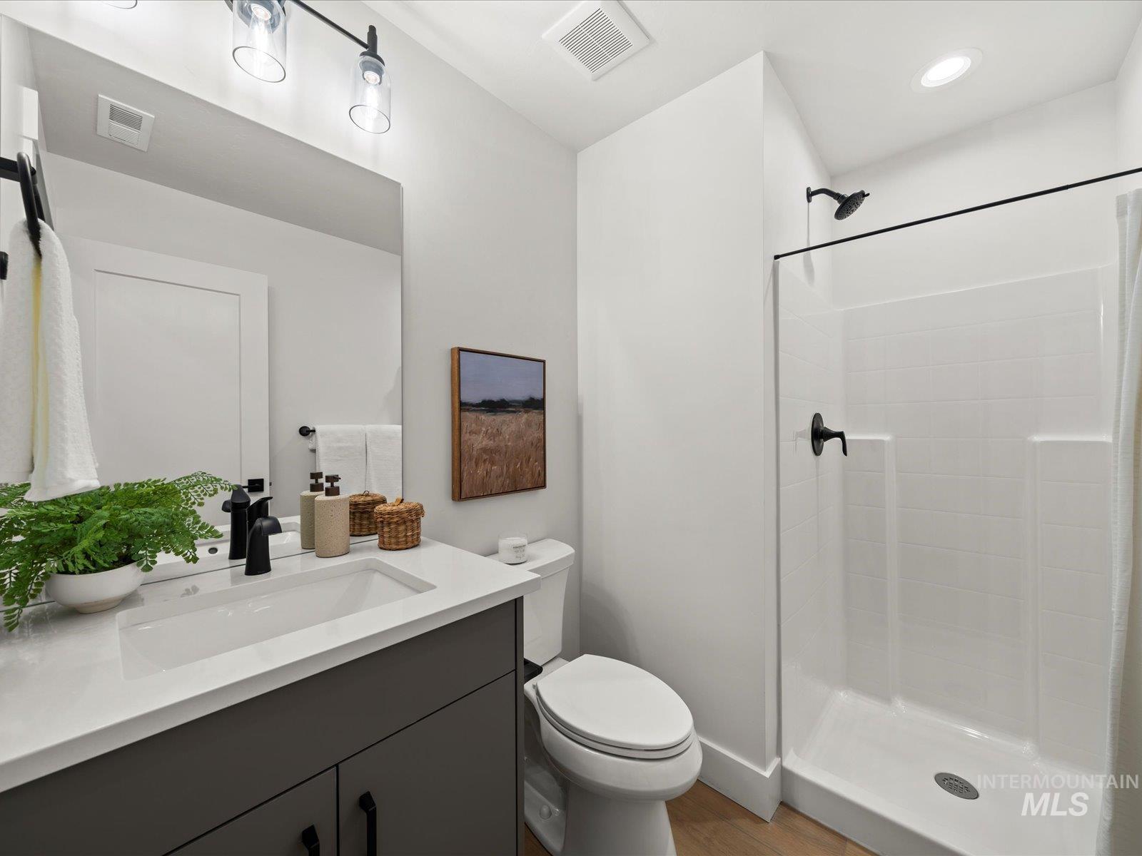 Bathroom featuring vanity, a shower stall, dark wood-style flooring, and recessed lighting