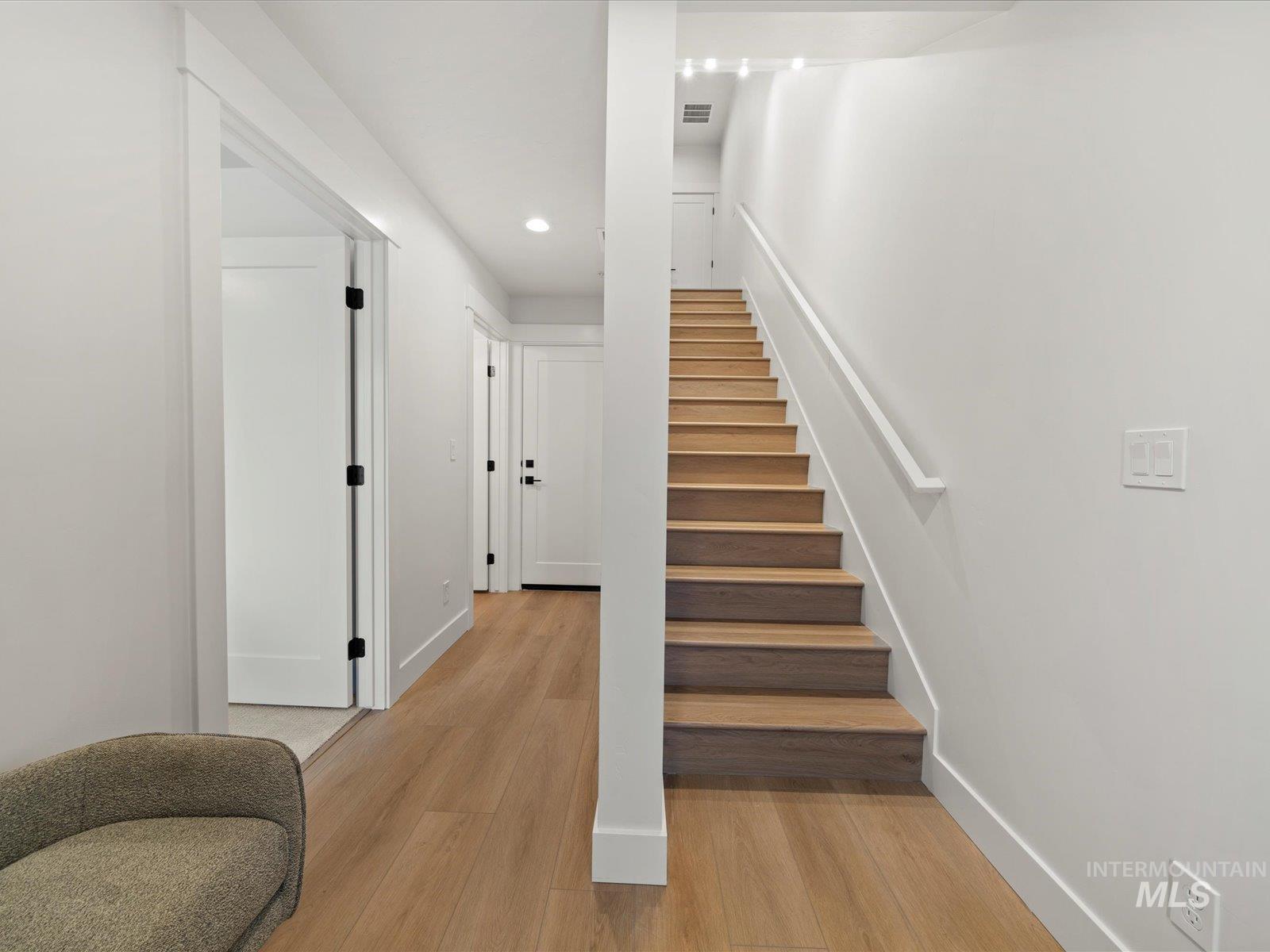 Stairway featuring wood finished floors and recessed lighting
