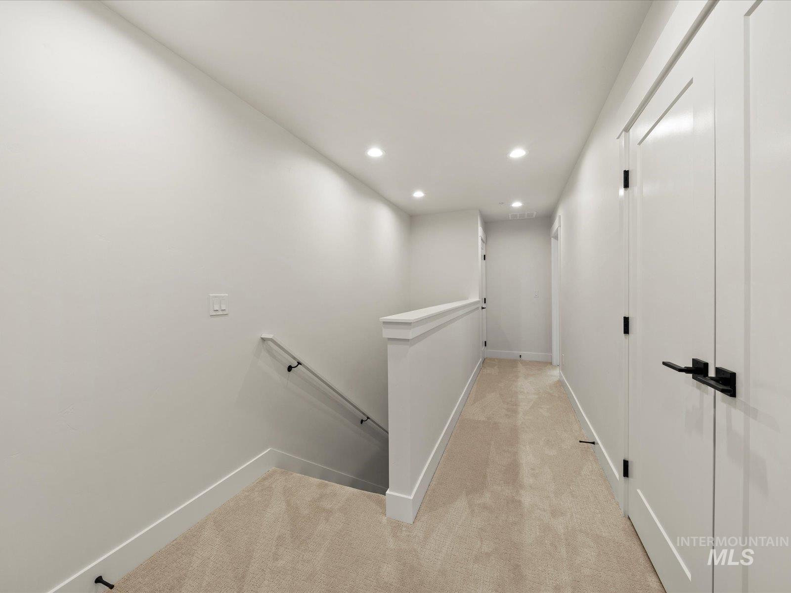 Hallway featuring recessed lighting, light carpet, and an upstairs landing