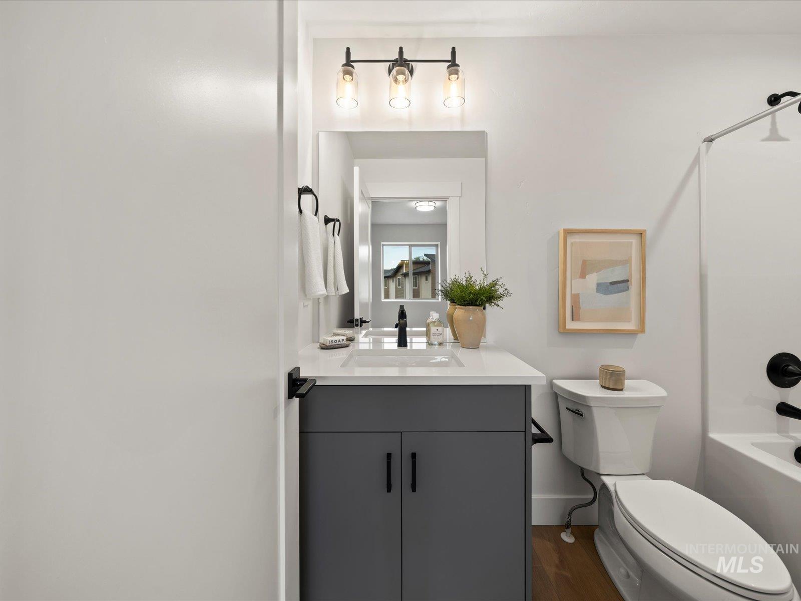 Full bathroom featuring dark wood-style flooring, vanity, and tub / shower combination