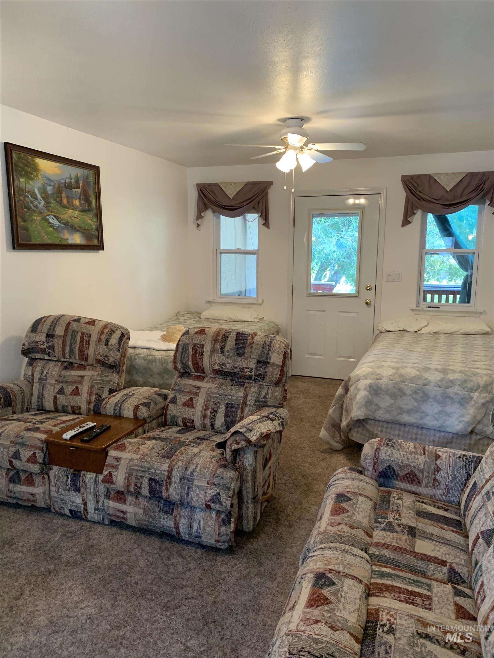Carpeted living area featuring ceiling fan