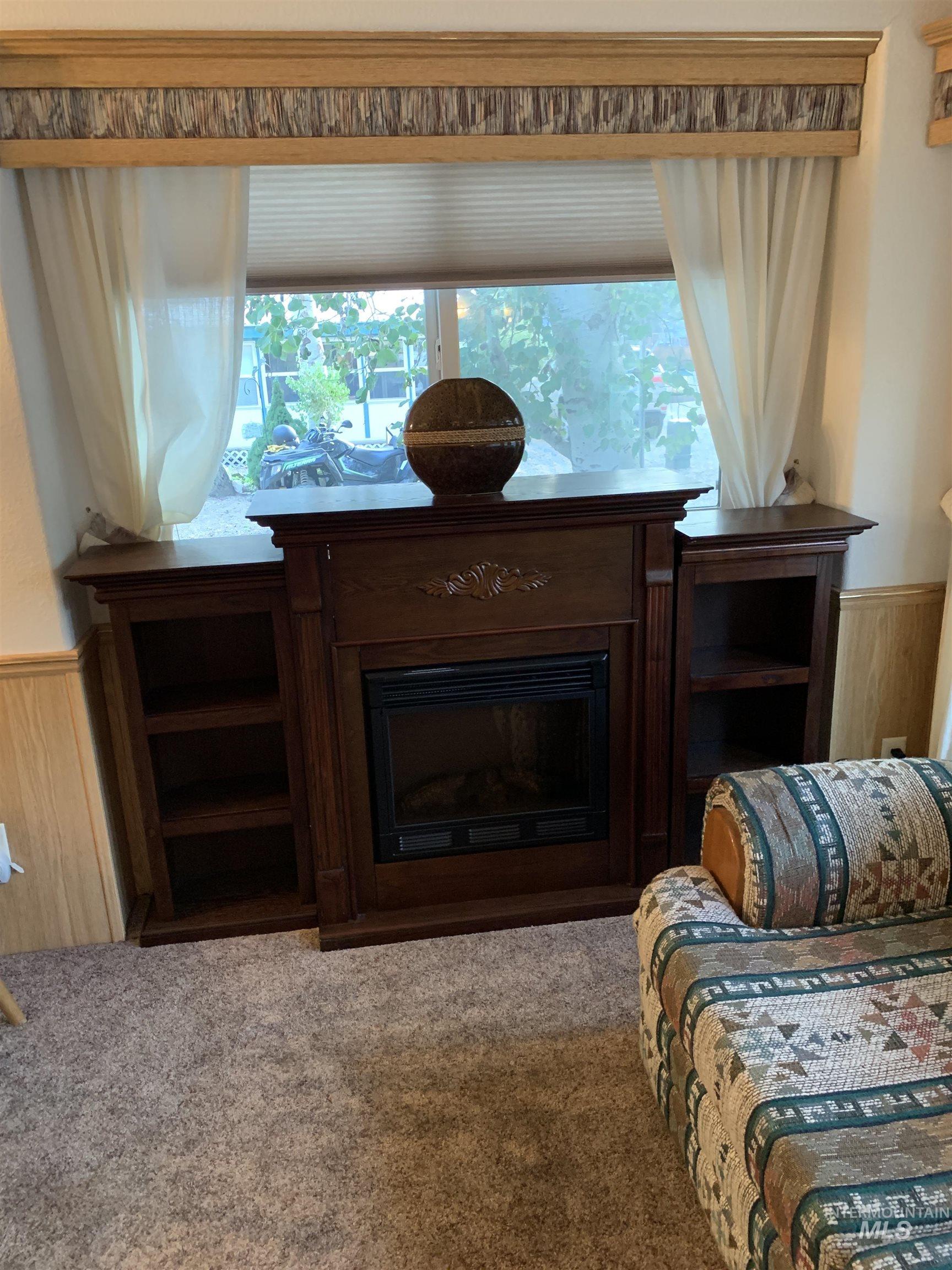 Living room featuring a wainscoted wall, wooden walls, a fireplace, and carpet