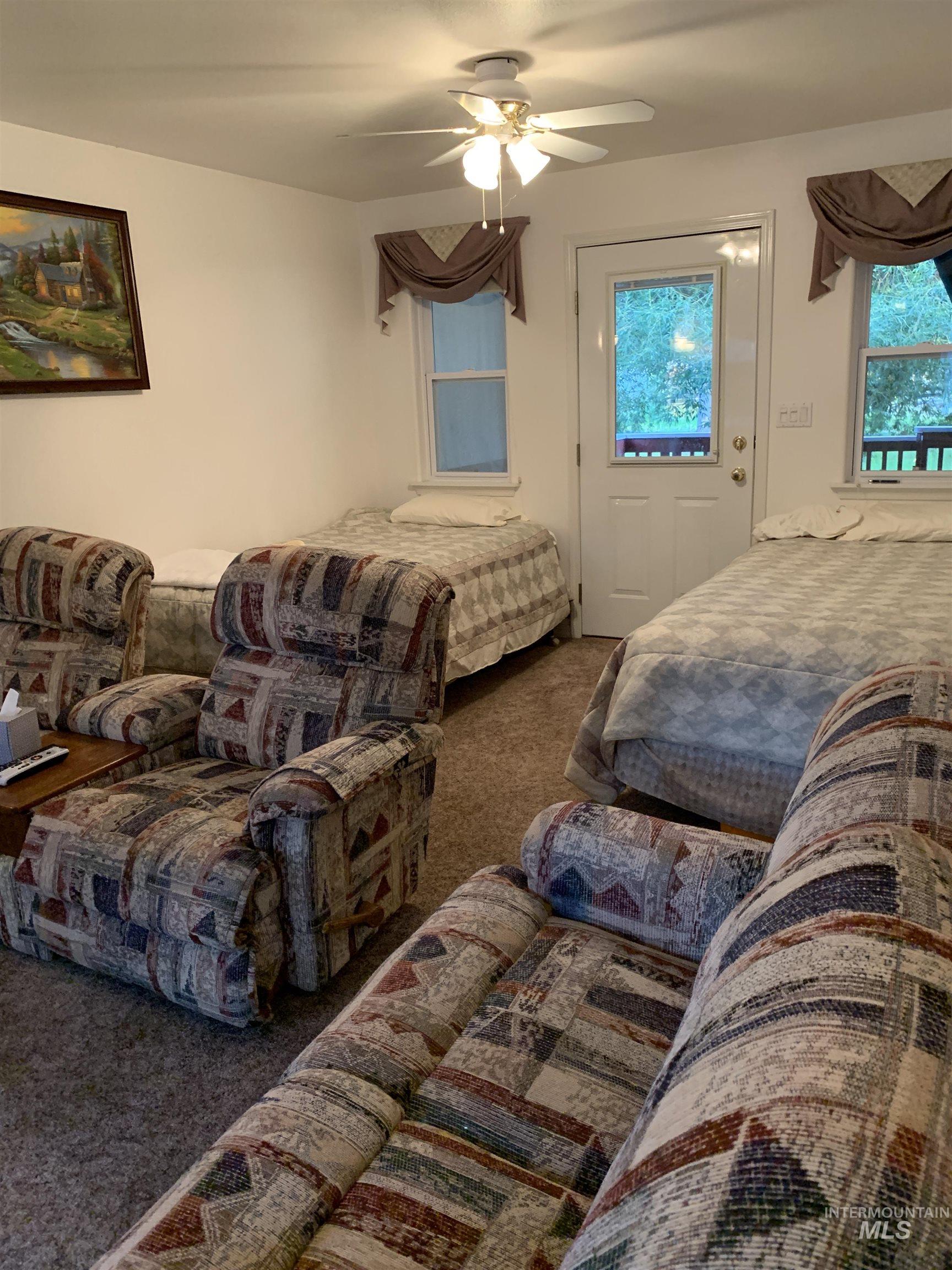 Carpeted bedroom with multiple windows and ceiling fan