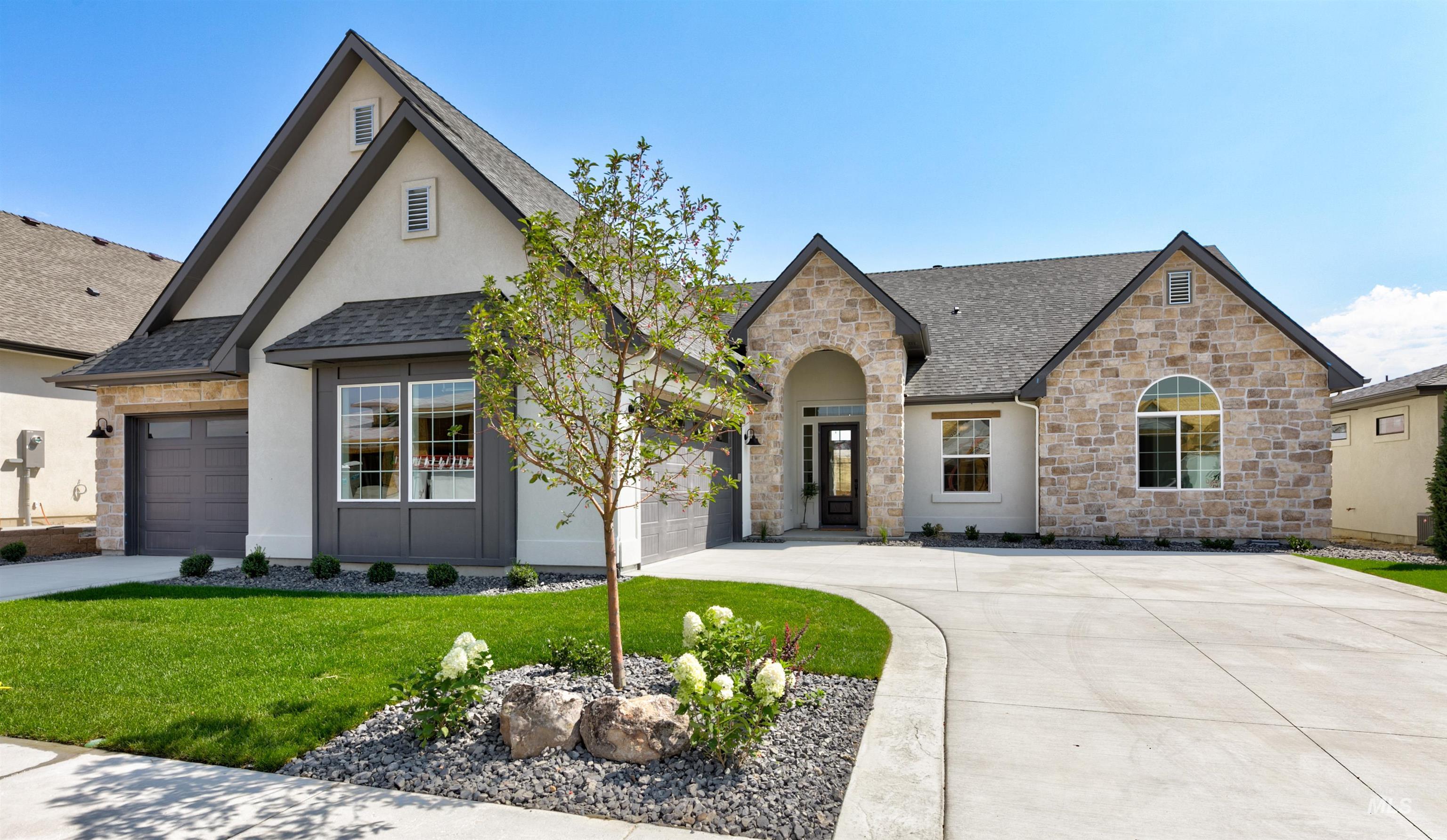 View of front of property with a shingled roof, stone siding, a front lawn, and concrete driveway