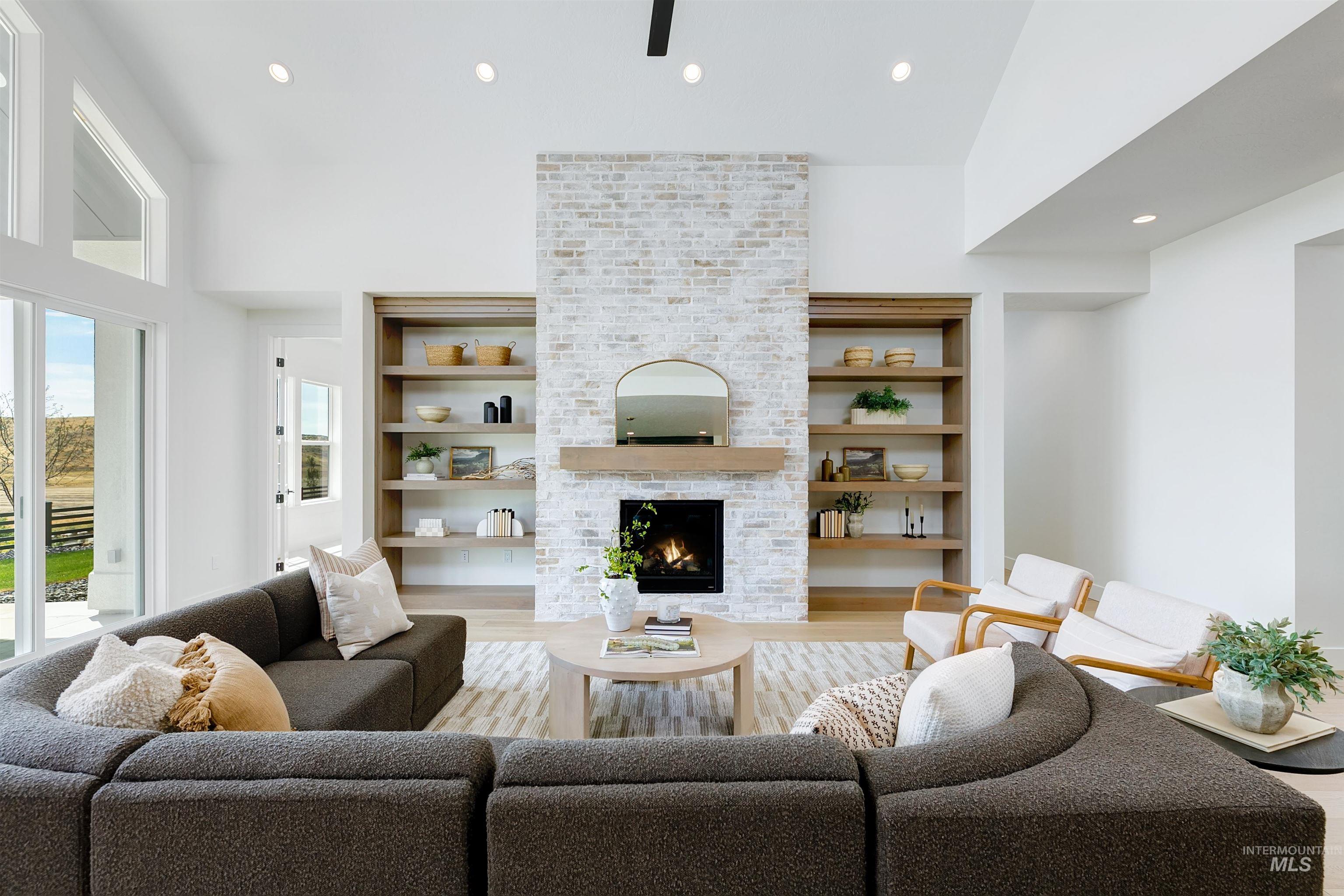 Living room with recessed lighting, a brick fireplace, light wood-type flooring, and a towering ceiling