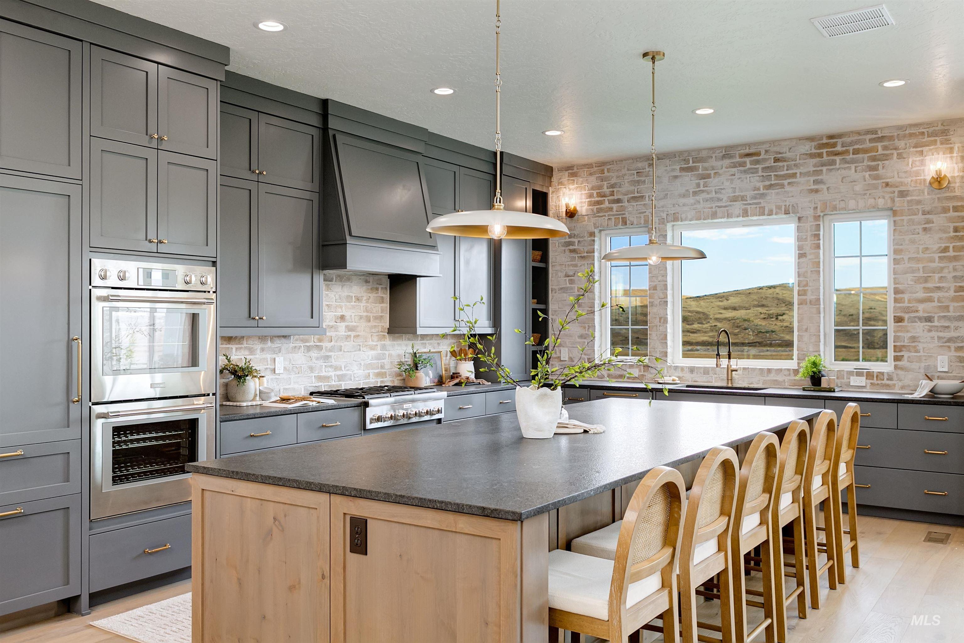 Kitchen featuring gray cabinetry, a kitchen island, stainless steel double oven, light wood finished floors, and hanging light fixtures