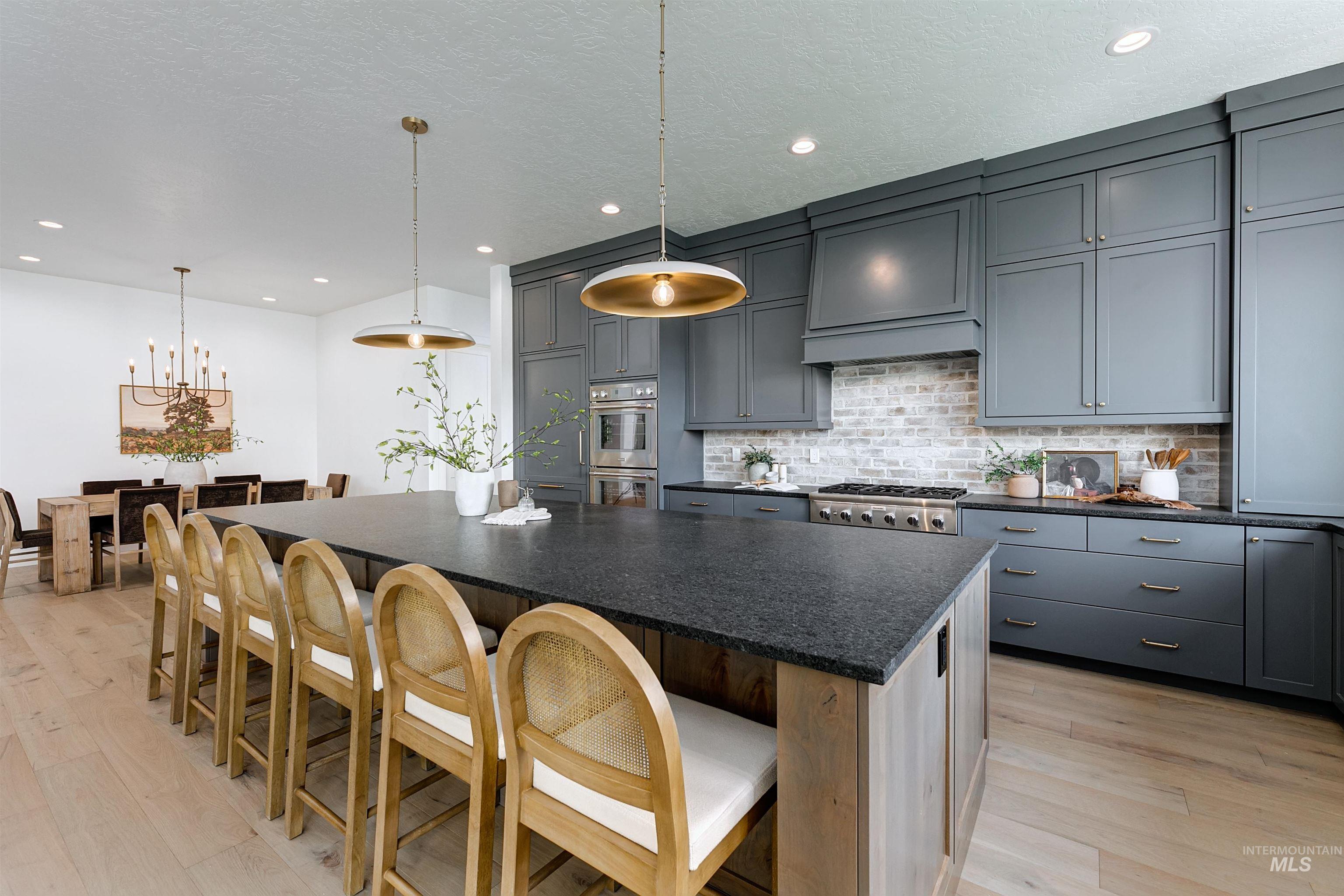 Kitchen with decorative light fixtures, gray cabinets, a breakfast bar, decorative backsplash, and light wood-style flooring