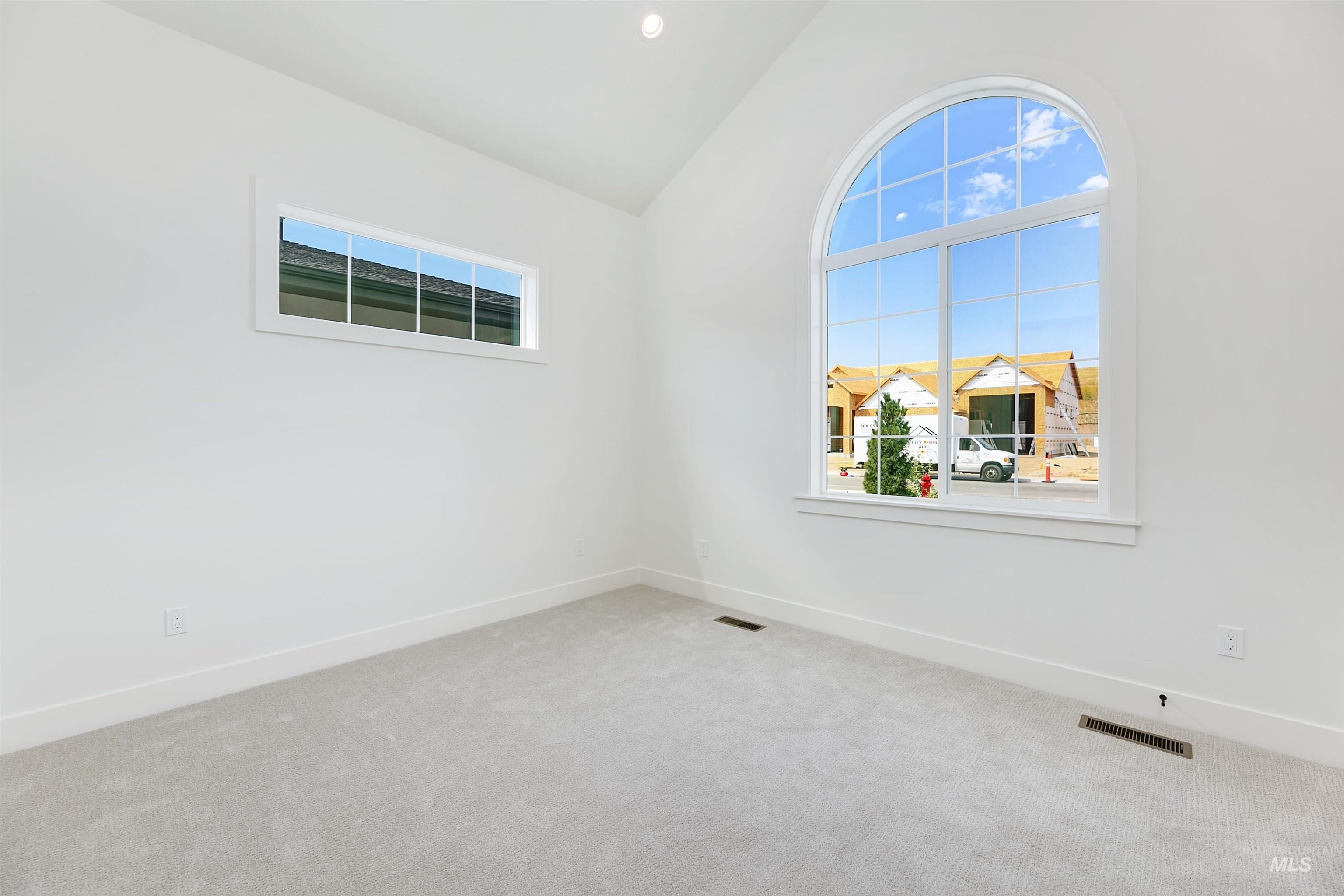 Carpeted spare room featuring vaulted ceiling and recessed lighting