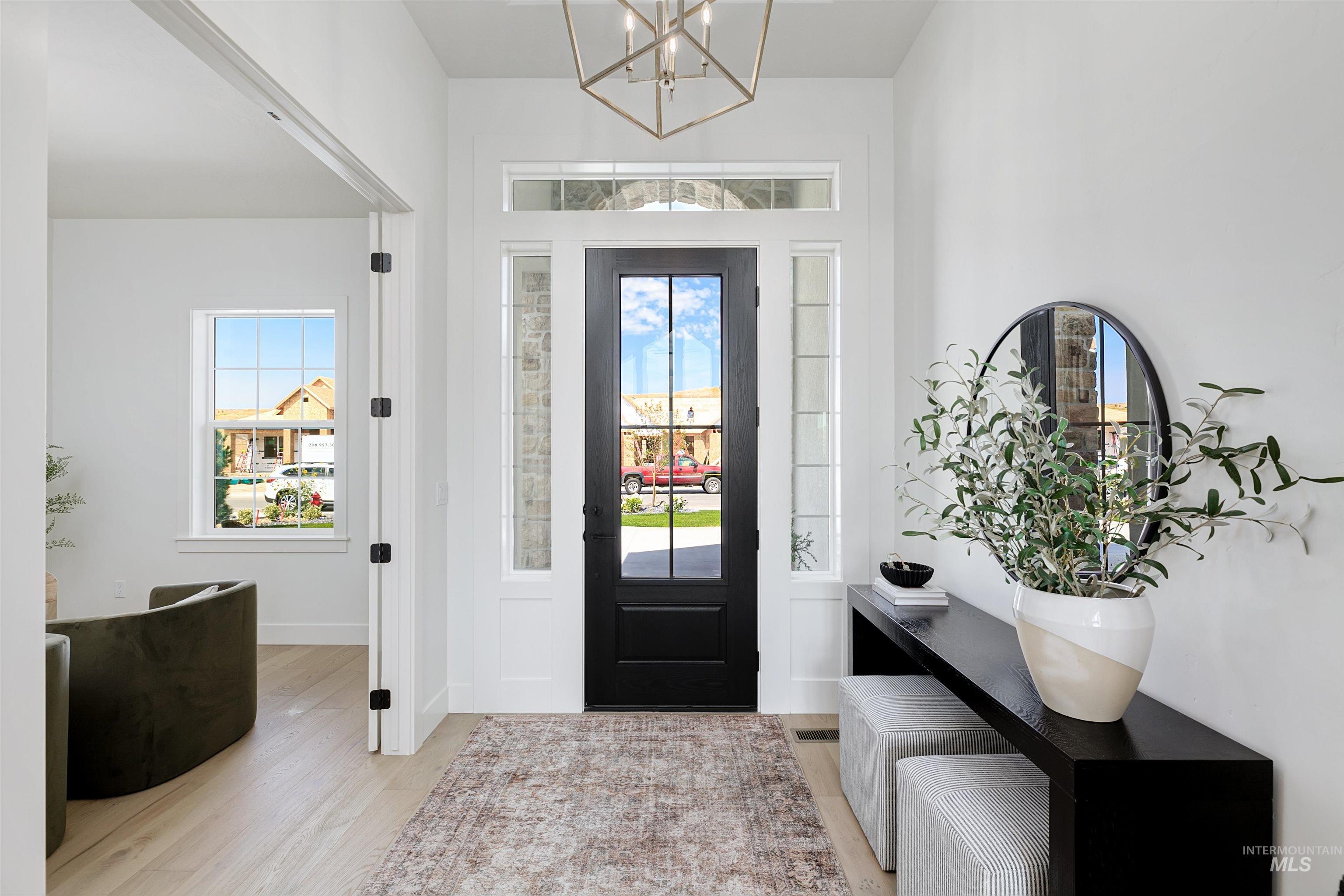 Entrance foyer with healthy amount of natural light, light wood-style flooring, and a chandelier