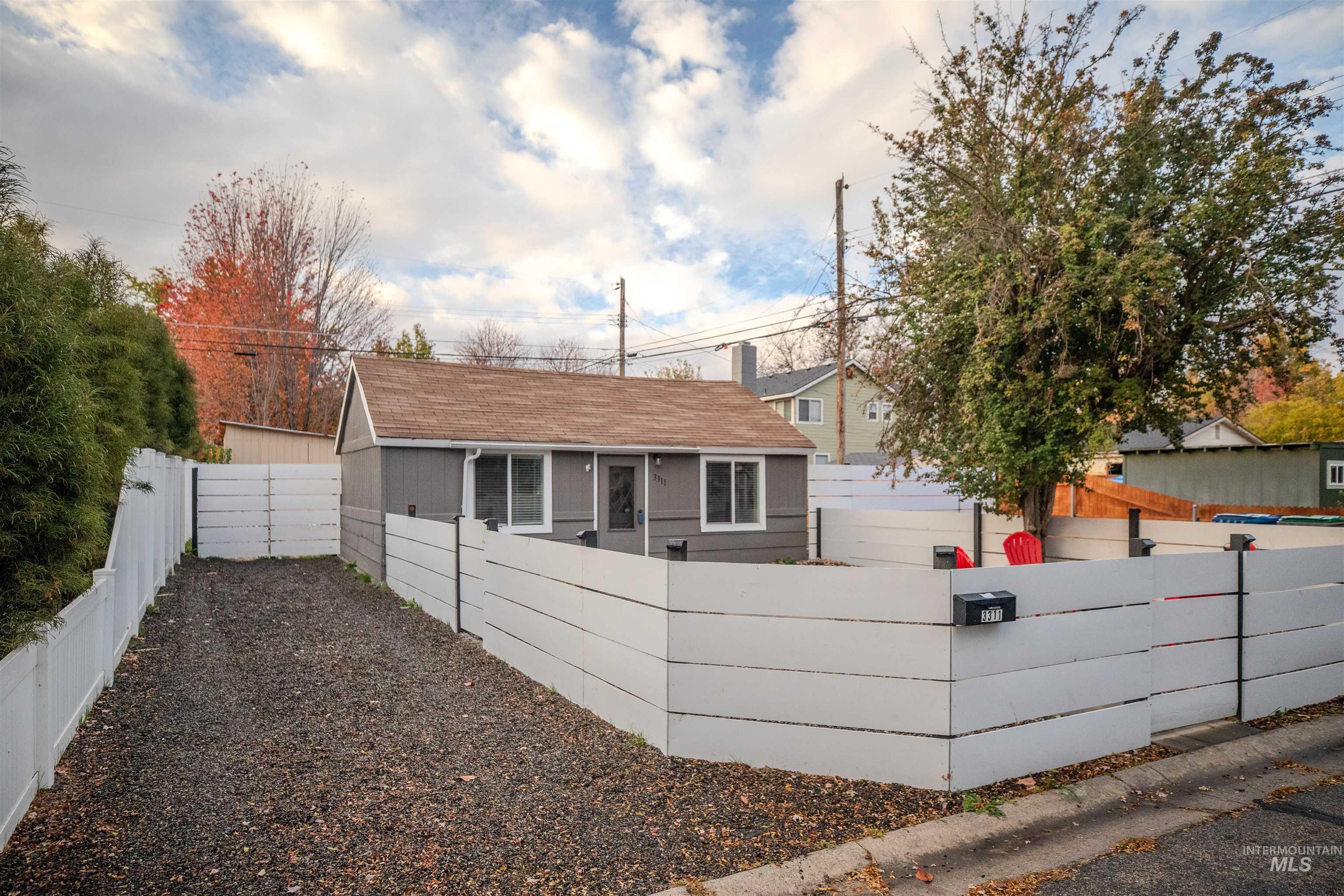 Driveway of property featuring a fenced front and back yard and a shingled roof