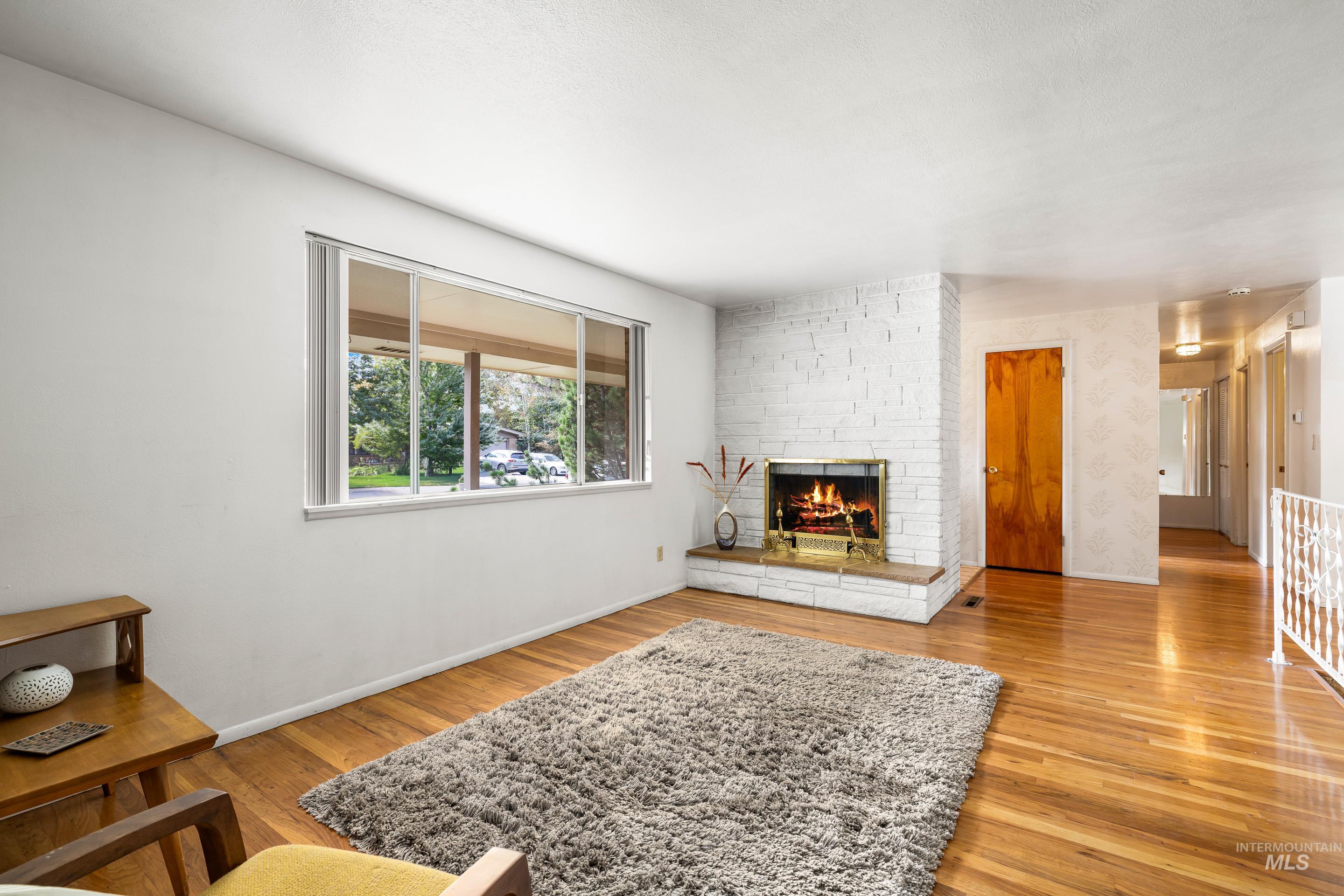 Living area featuring light wood finished floors, a brick fireplace, and wallpapered walls