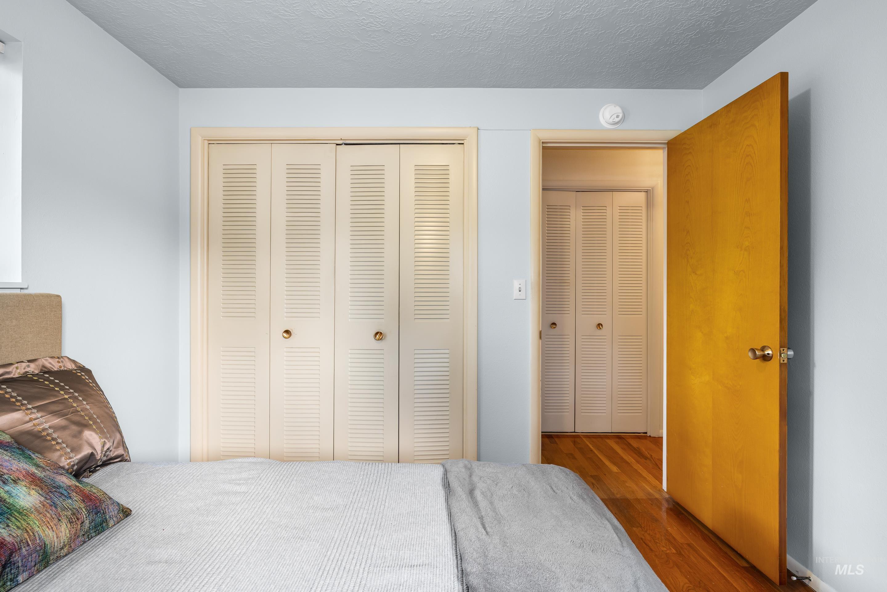 Bedroom with dark wood-style floors, a textured ceiling, and a closet