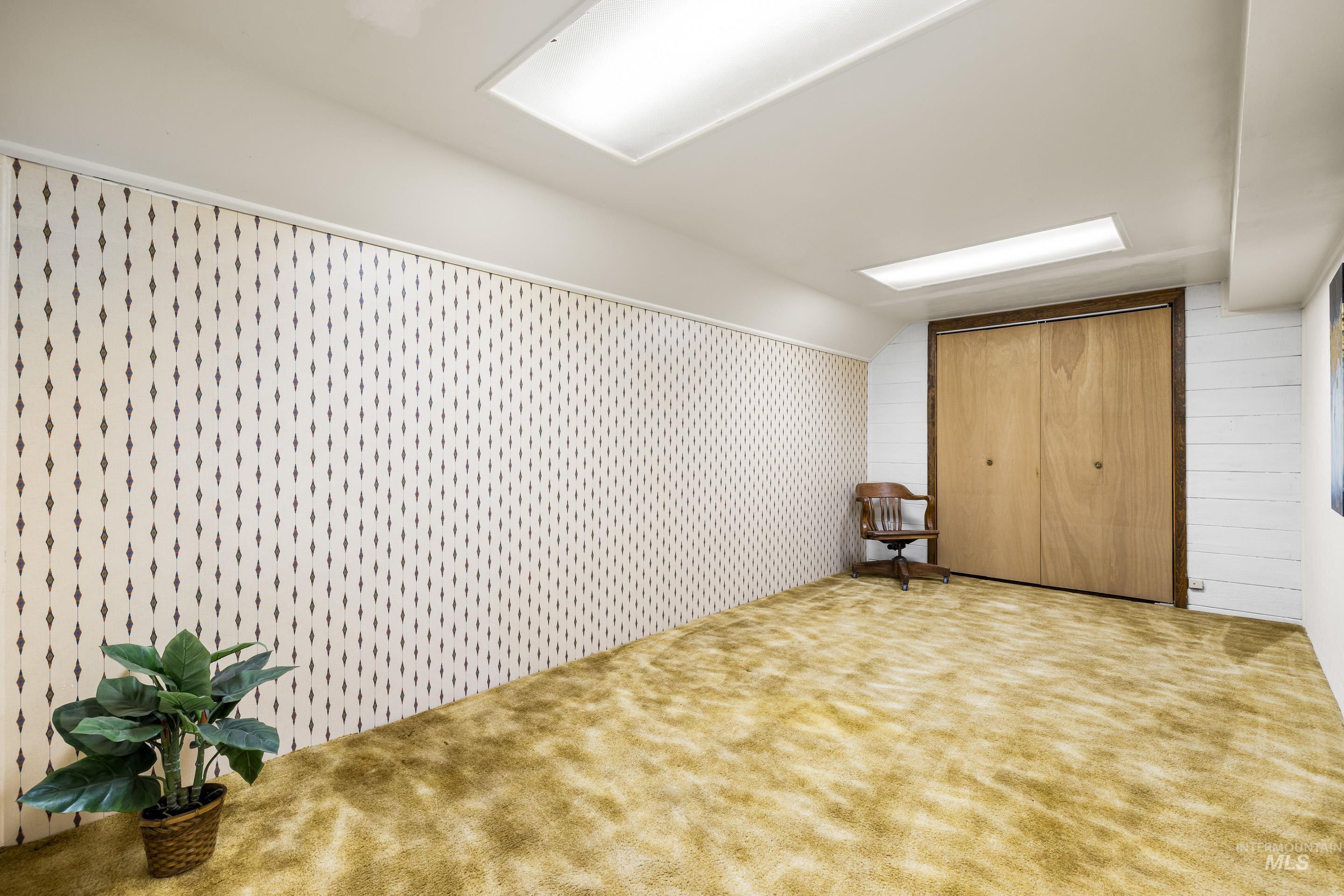 Additional living space featuring carpet flooring, lofted ceiling, and wallpapered walls