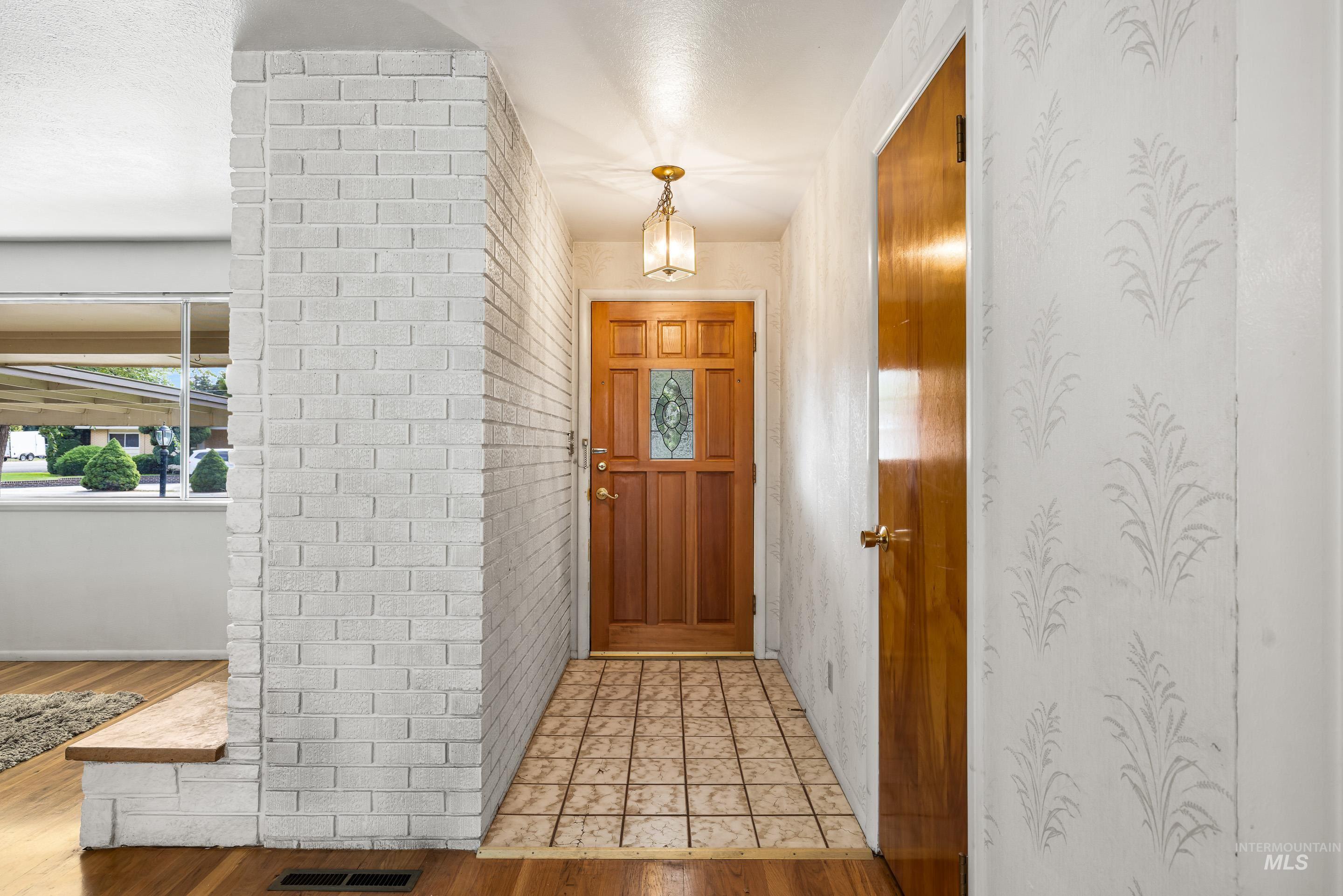 Foyer entrance featuring light wood finished floors and brick wall