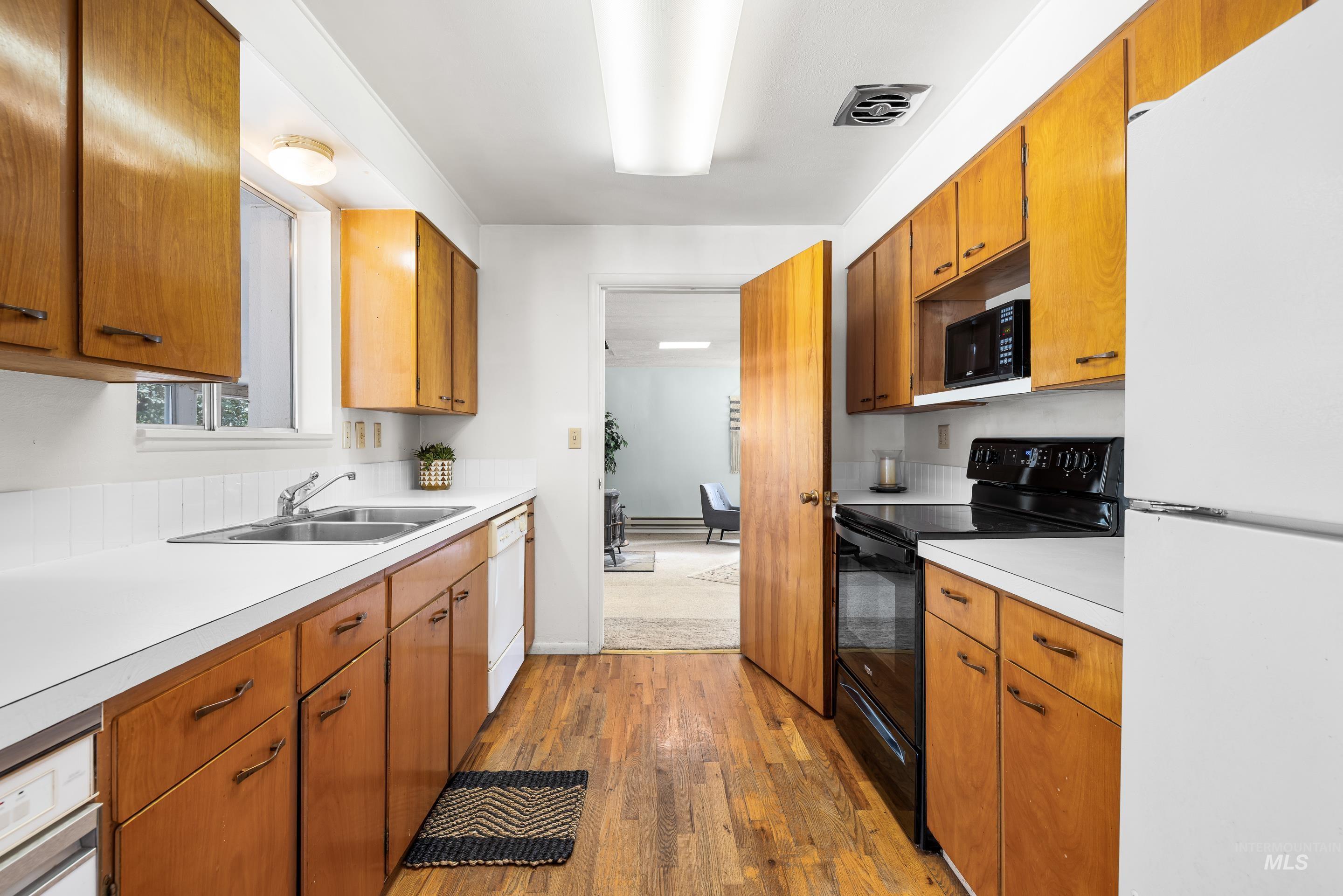 Kitchen featuring white appliances, light wood-style floors, light countertops, and brown cabinets