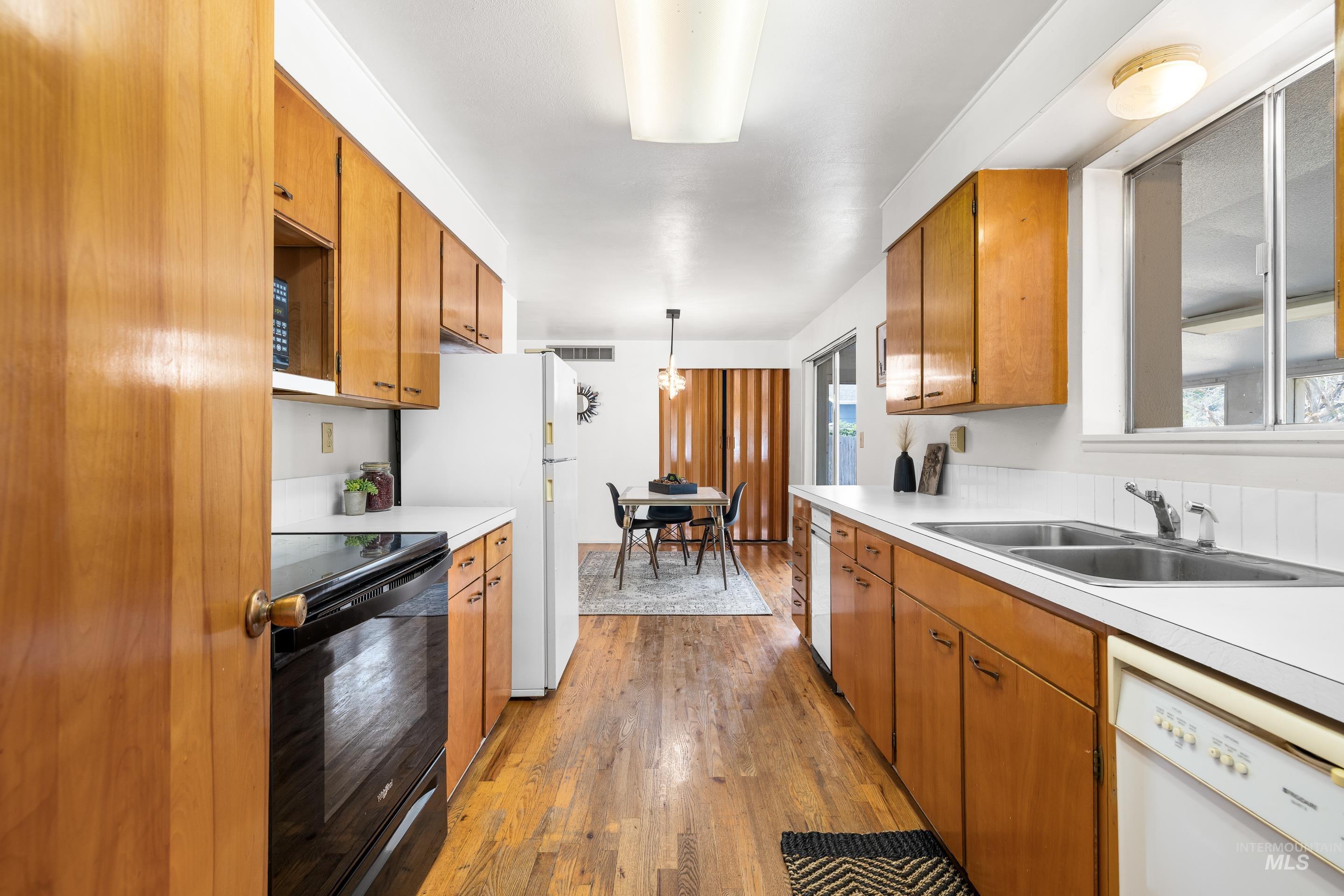 Kitchen featuring brown cabinets, white appliances, and light wood finished floors