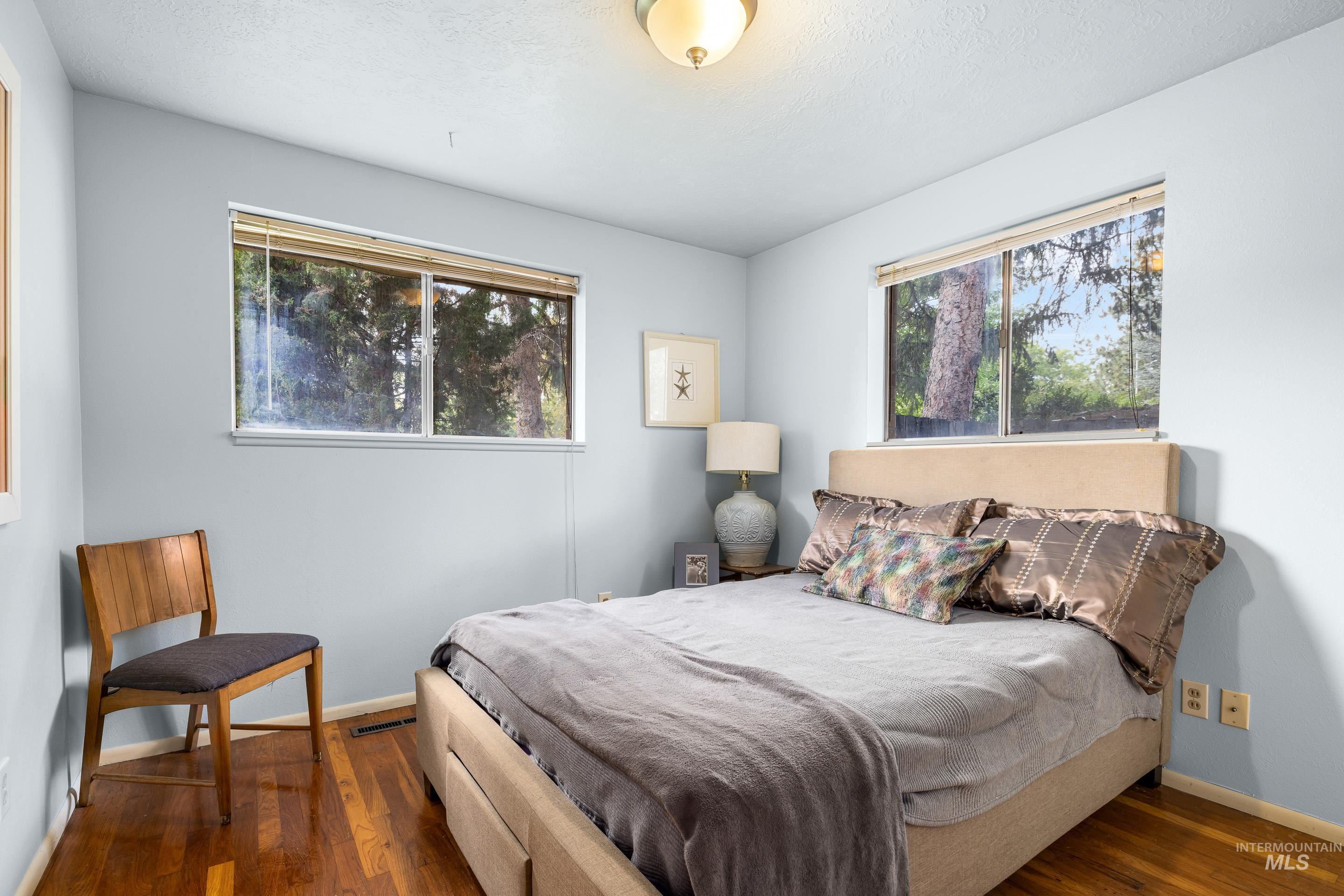 Bedroom featuring dark wood finished floors and multiple windows