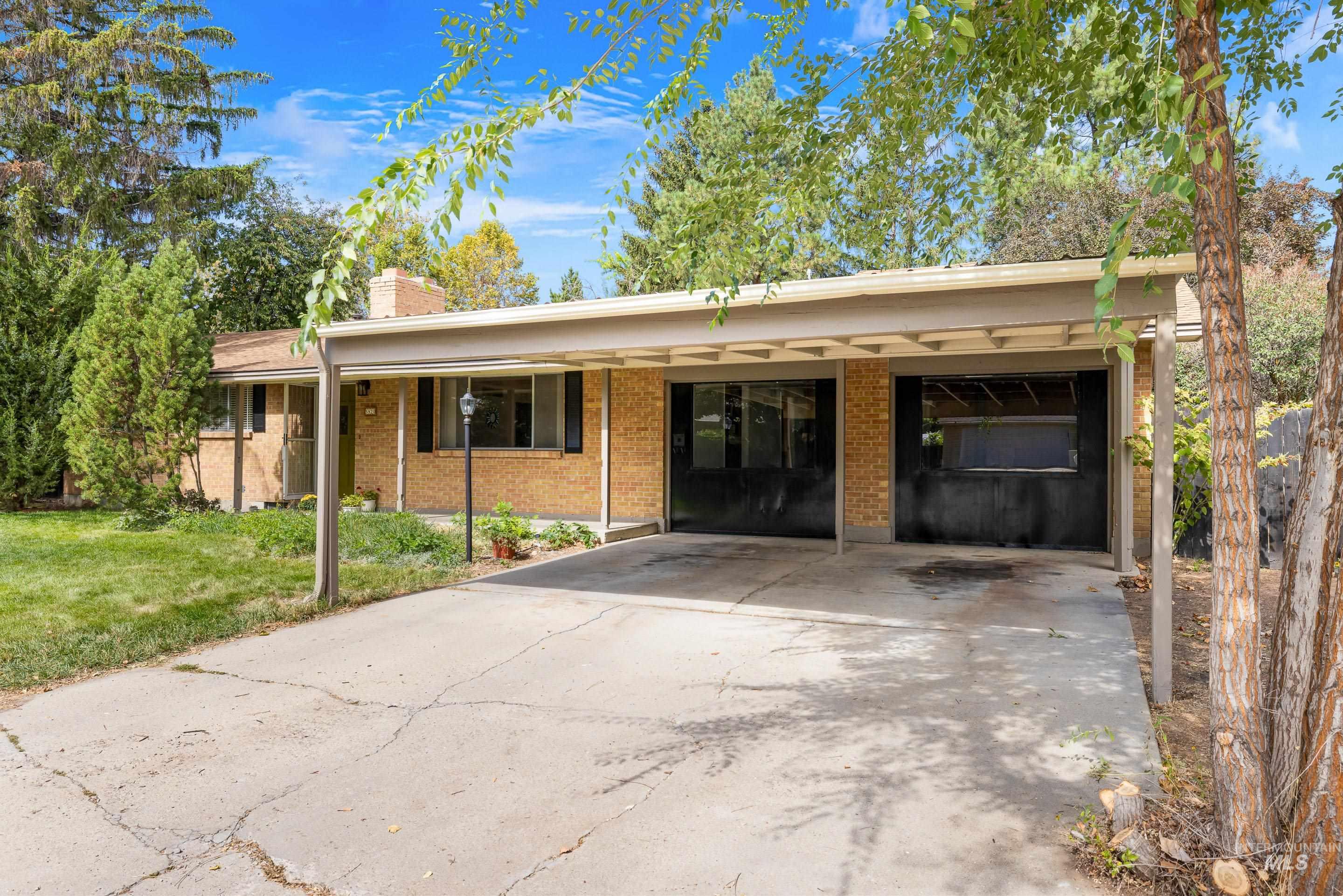 Ranch-style home featuring brick siding, a front yard, a chimney, and driveway