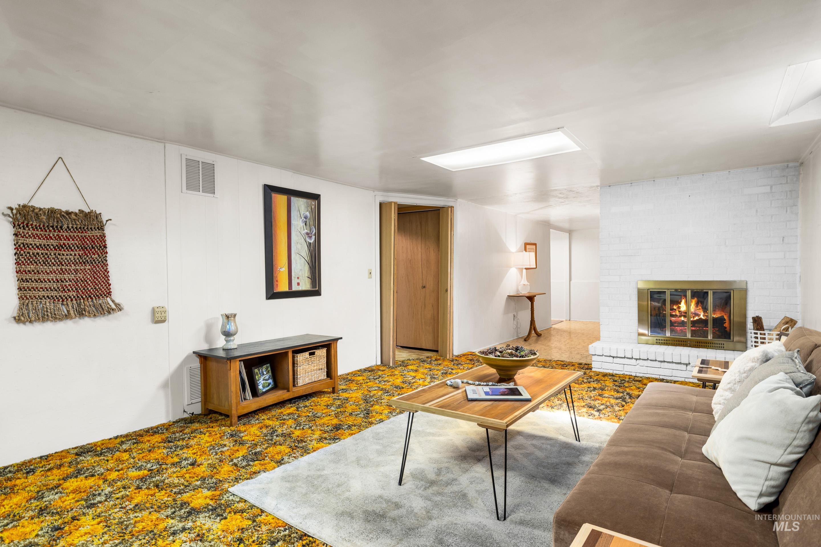 Carpeted living room featuring a brick fireplace