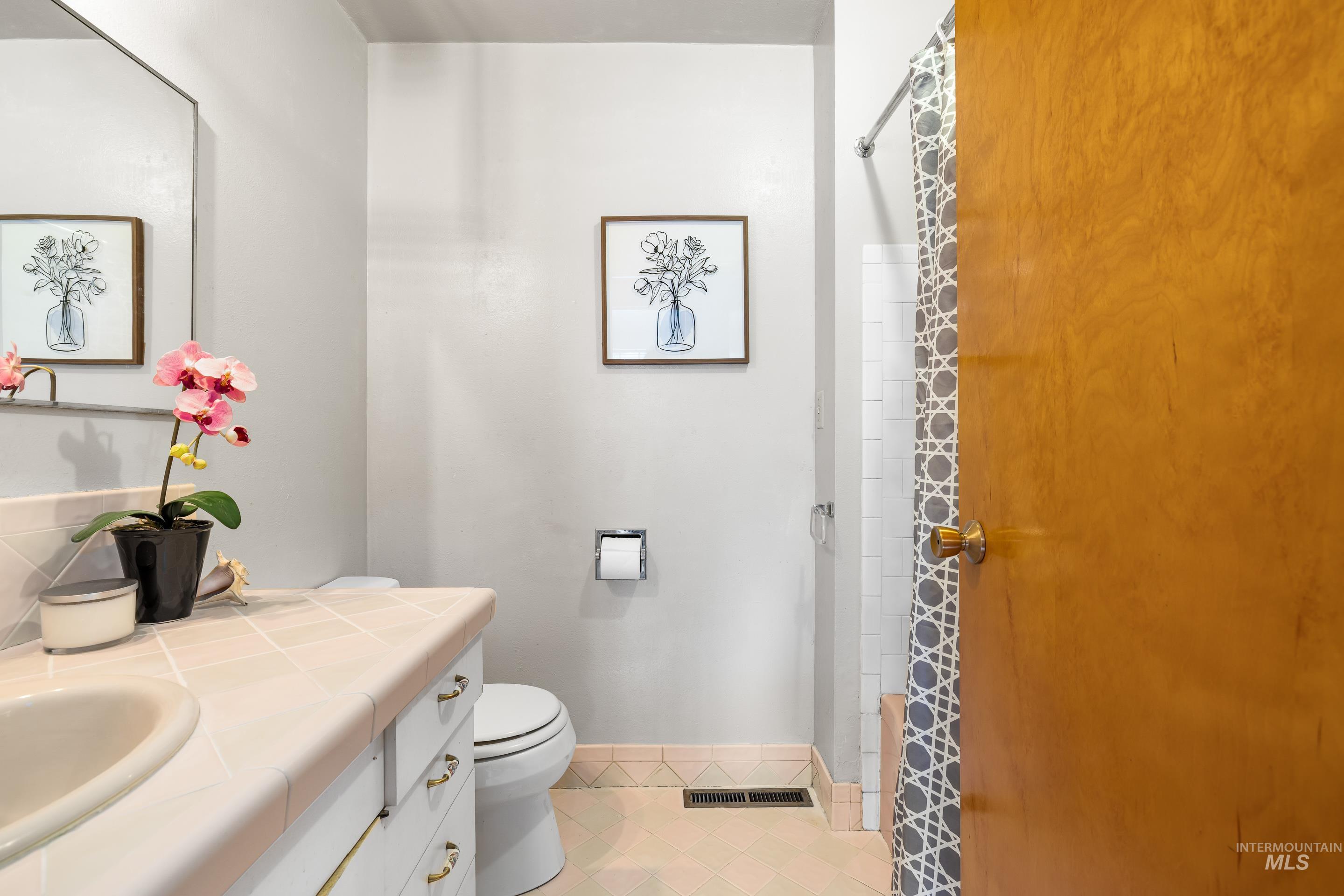 Full bath with vanity, curtained shower, and light tile patterned floors