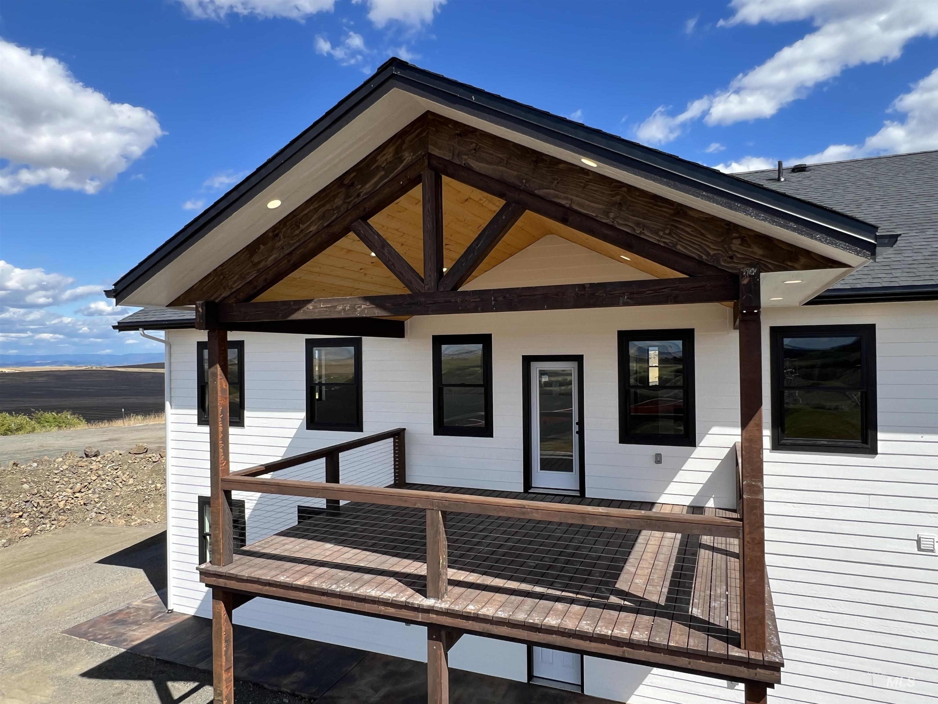 Entrance to property featuring a shingled roof and covered porch