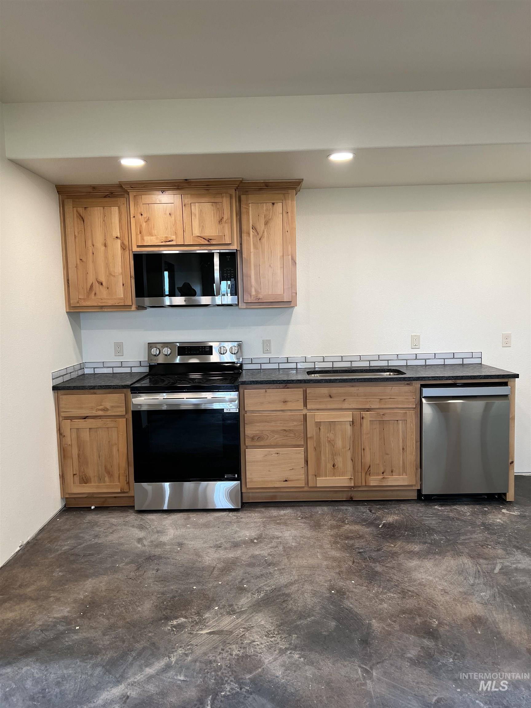 Kitchen with concrete flooring, appliances with stainless steel finishes, and recessed lighting