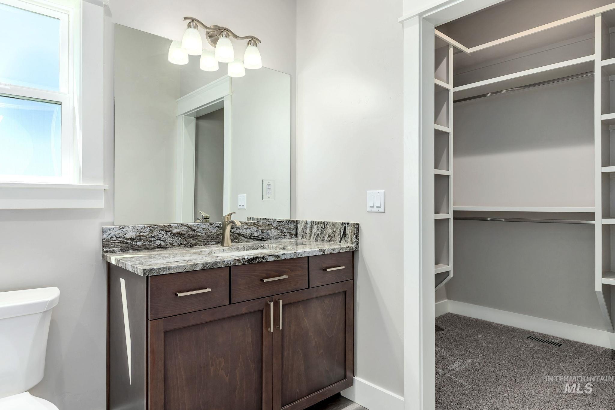 Bathroom featuring vanity and a walk in closet
