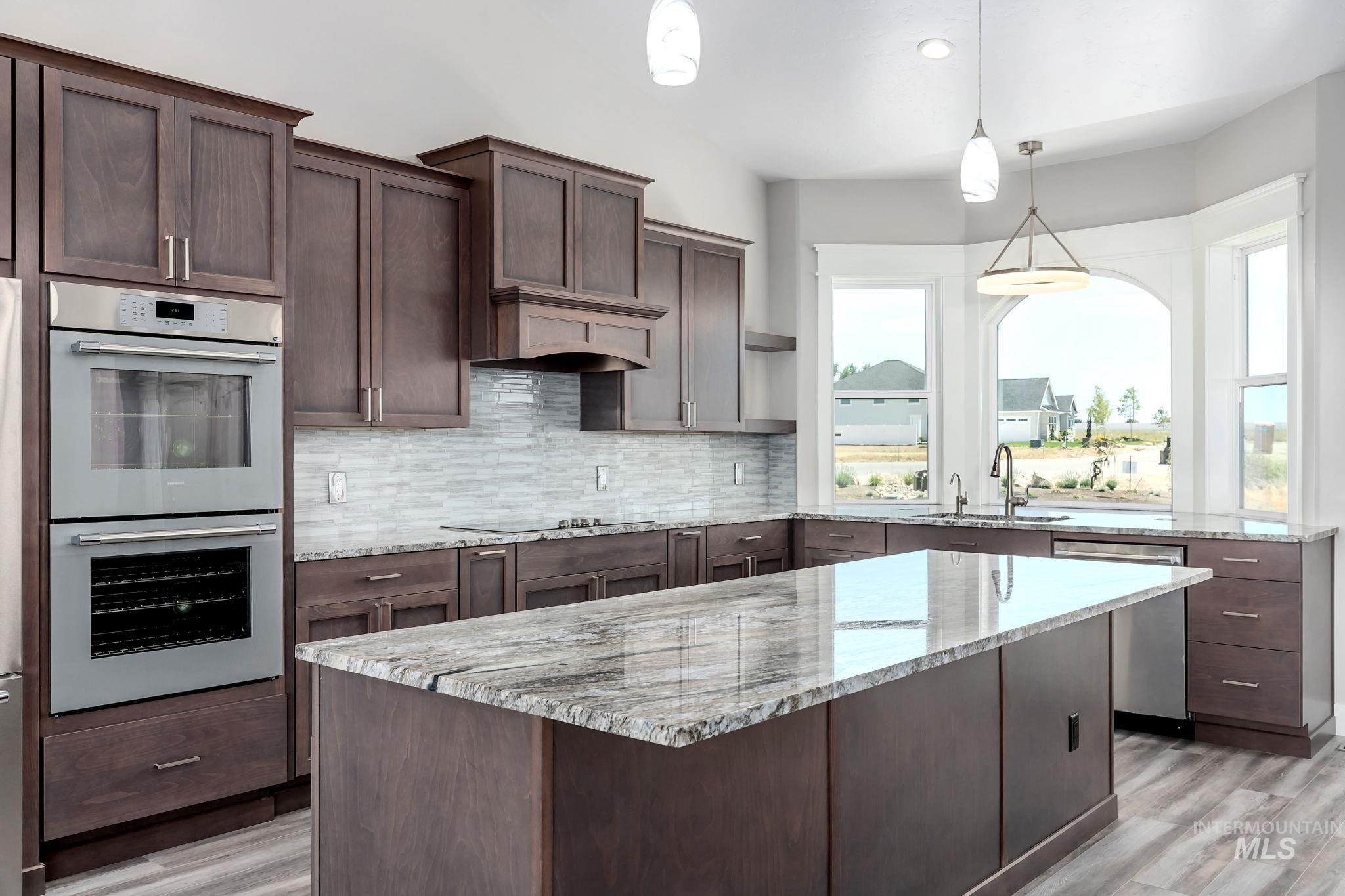 Kitchen with stainless steel appliances, light wood-style flooring, backsplash, and dark brown cabinetry