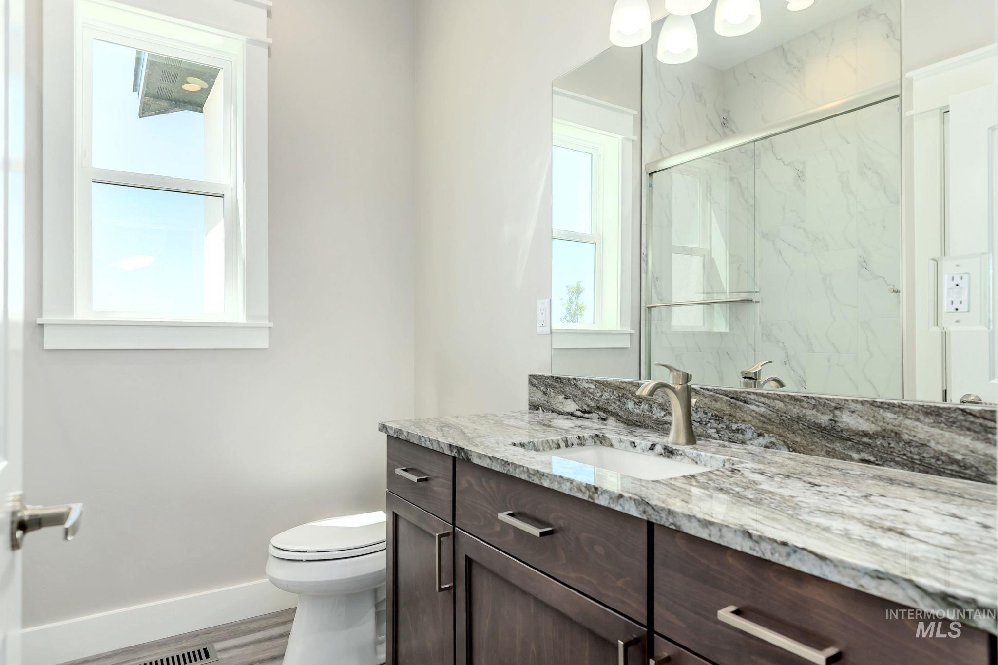 Bathroom featuring vanity, a marble finish shower, and wood finished floors