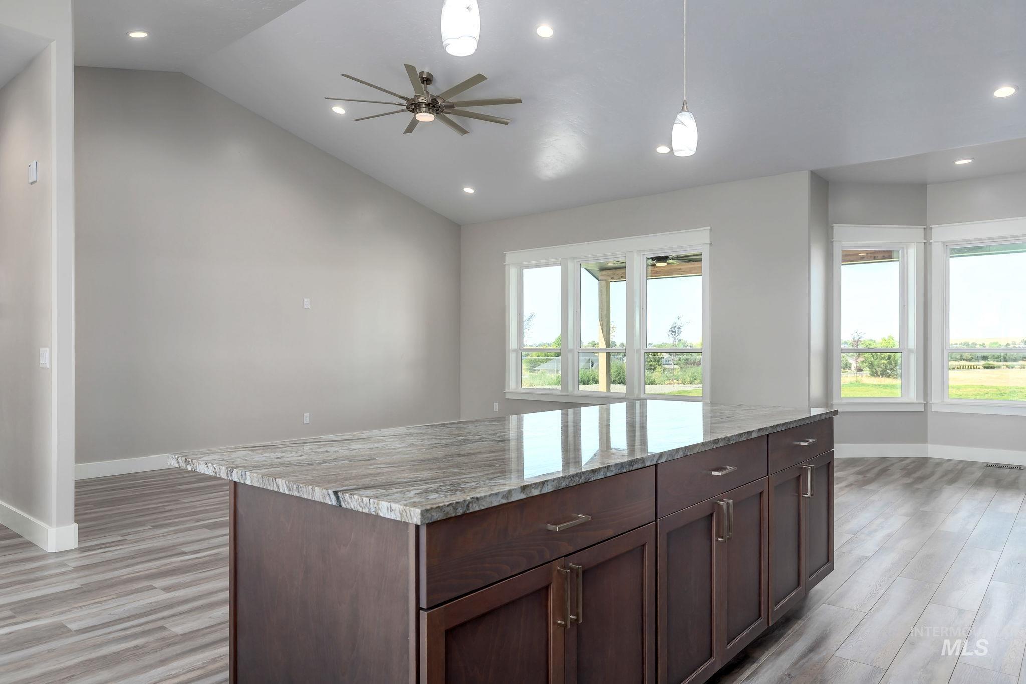 Kitchen featuring vaulted ceiling, light wood-style flooring, decorative light fixtures, a ceiling fan, and recessed lighting