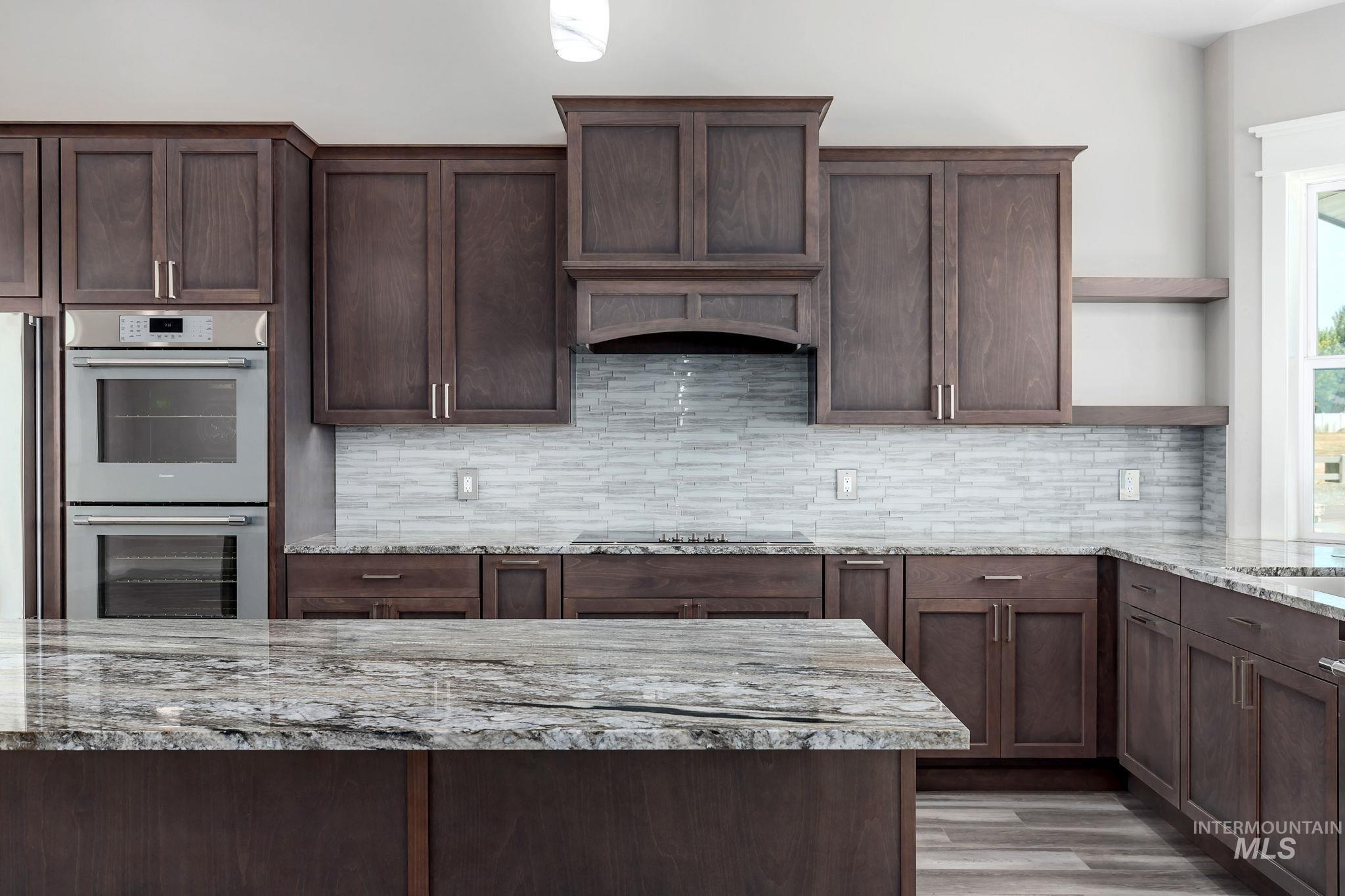 Kitchen with open shelves, double oven, tasteful backsplash, and wood finished floors
