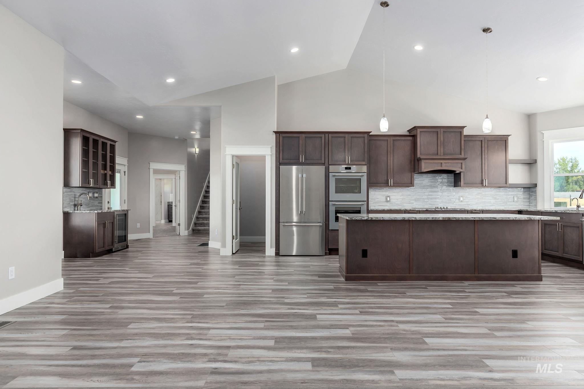 Kitchen featuring open shelves, appliances with stainless steel finishes, high vaulted ceiling, decorative backsplash, and light wood-type flooring