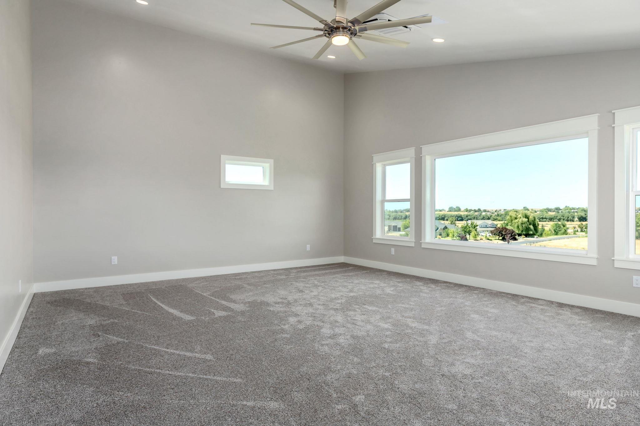 Carpeted empty room with plenty of natural light, a ceiling fan, and recessed lighting