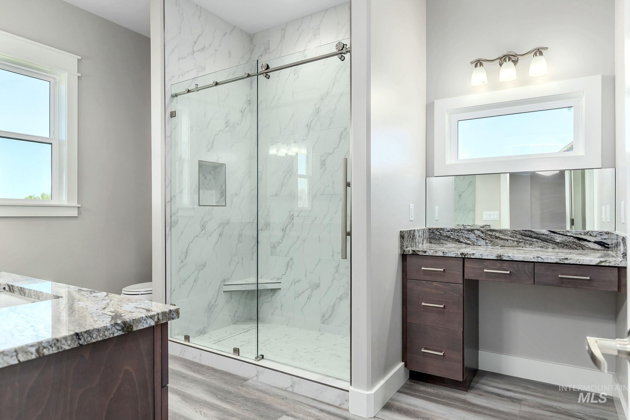 Full bathroom featuring vanity, a marble finish shower, and wood finished floors