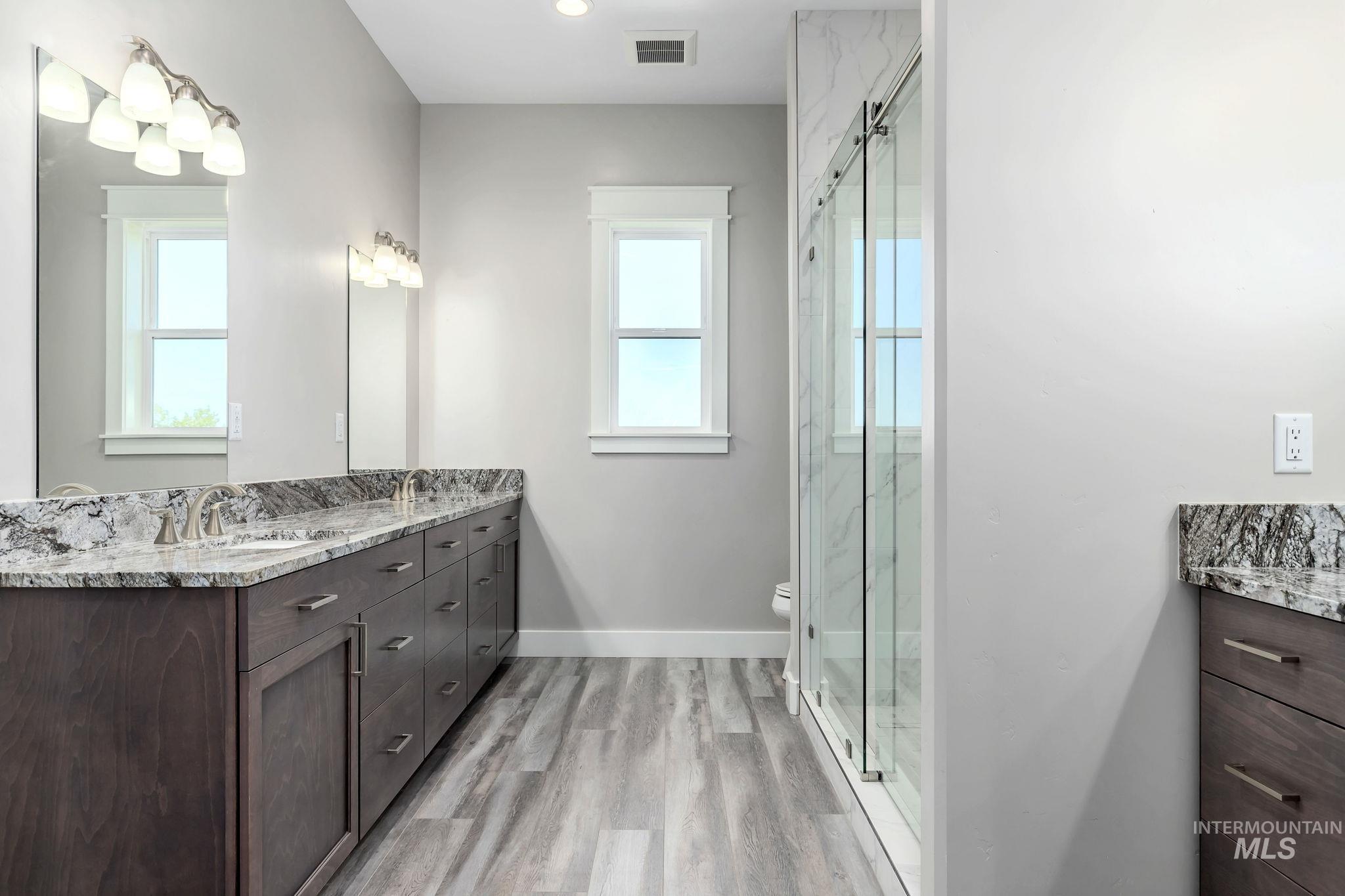 Full bath featuring vanity, wood finished floors, and a marble finish shower