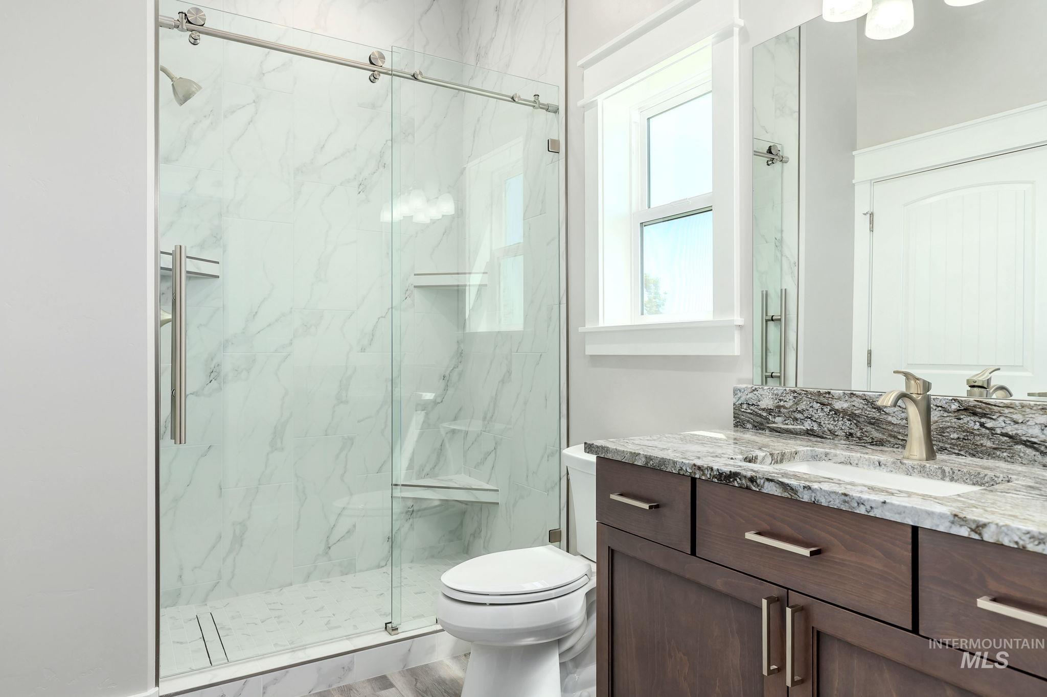 Full bath featuring vanity and a marble finish shower