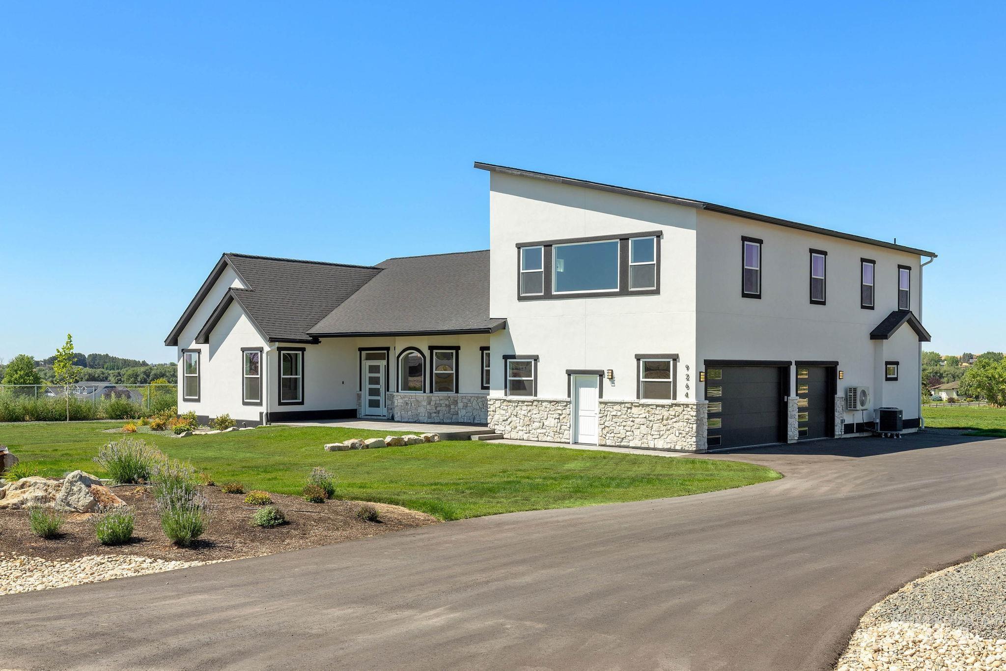 View of front facade featuring a garage, stucco siding, a front lawn, asphalt driveway, and stone siding